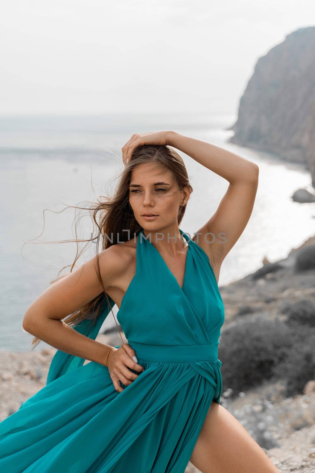 Woman sea green dress. Side view a happy woman with long hair in a long mint dress posing on a beach with calm sea bokeh lights on sunny day. Girl on the nature on blue sky background. by Matiunina