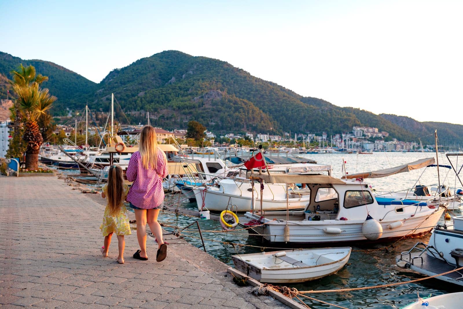 Walking mother and little daughter on seaside city embankment by Fabrikasimf