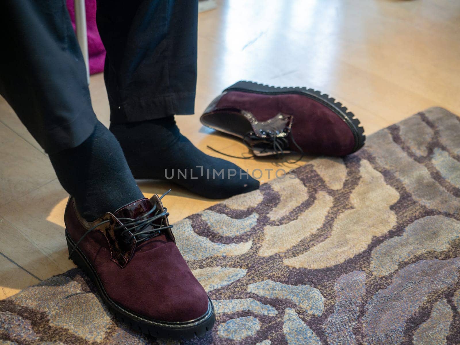 unrecognizable woman in the shop trying new shoes. Caucasian woman sitting in a shoe store while chooses new pair of italian sneakers.