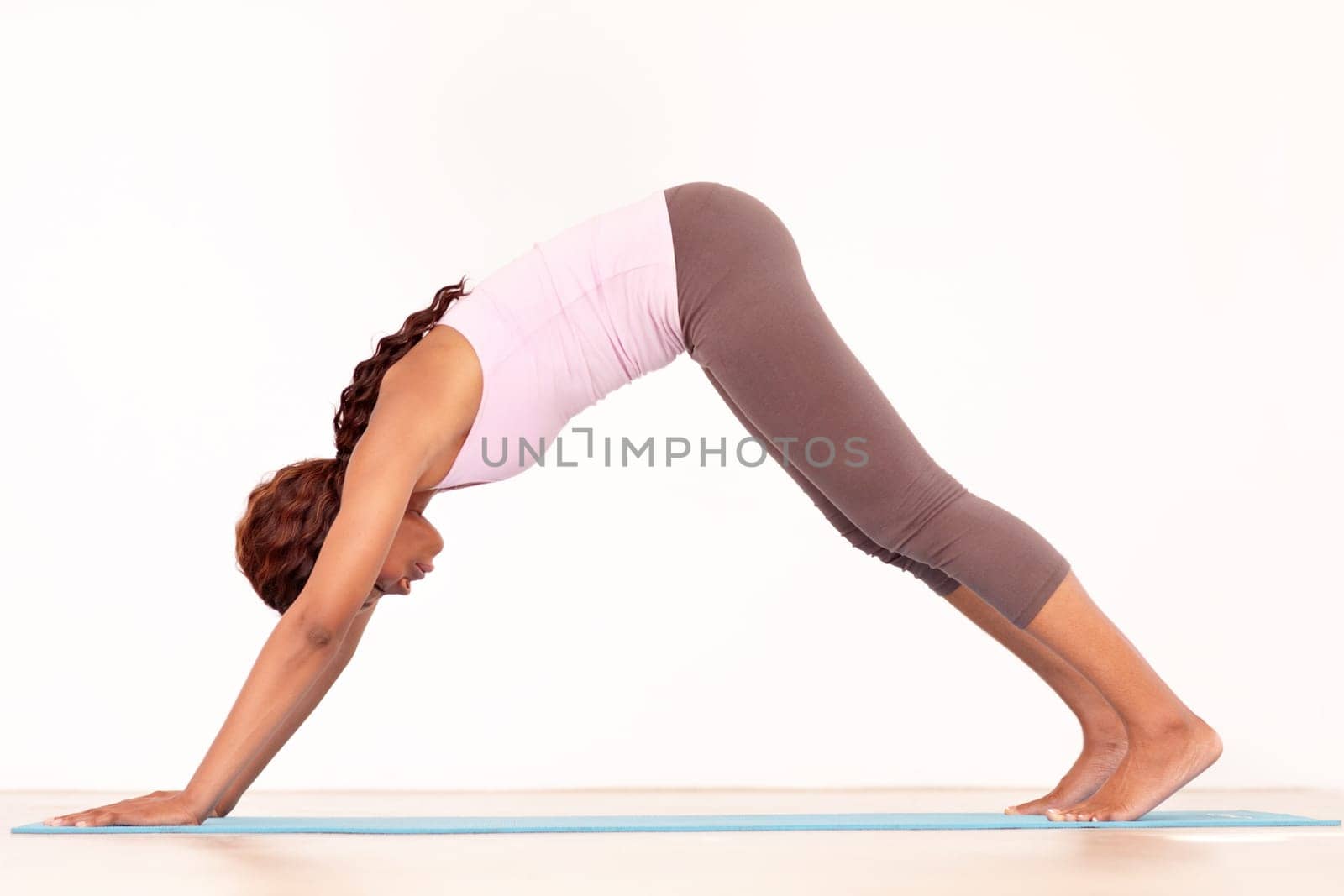 Yoga, body stretching and black woman in studio on a fitness and workout mat for training. Isolated, white background and African female person relax on the ground with downward dog for wellness.