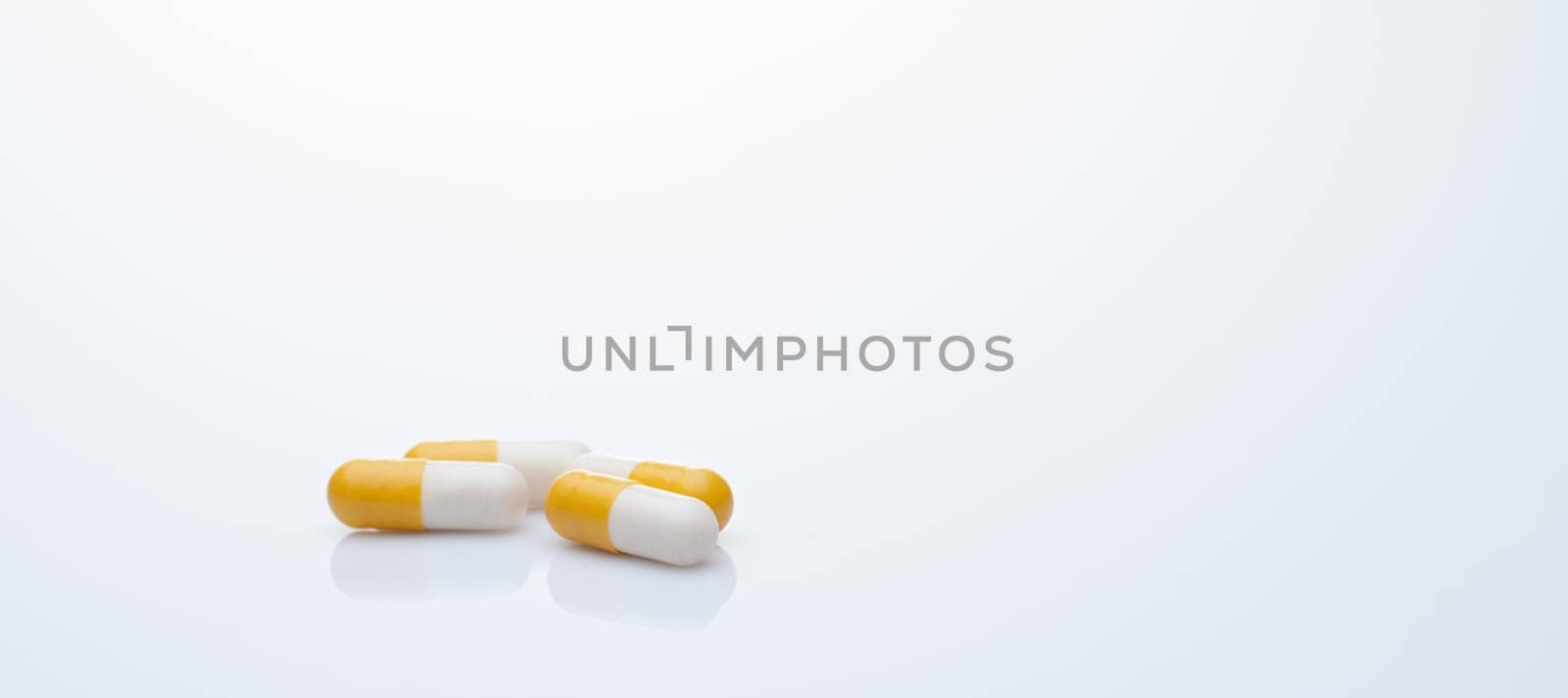 Yellow-white probiotic capsule pill on white background. Probiotic supplement. Gut health. Dietary supplements. Probiotics for a healthy gut. Lactobacillus acidophilus and Bifidobacterium animalis. by Fahroni