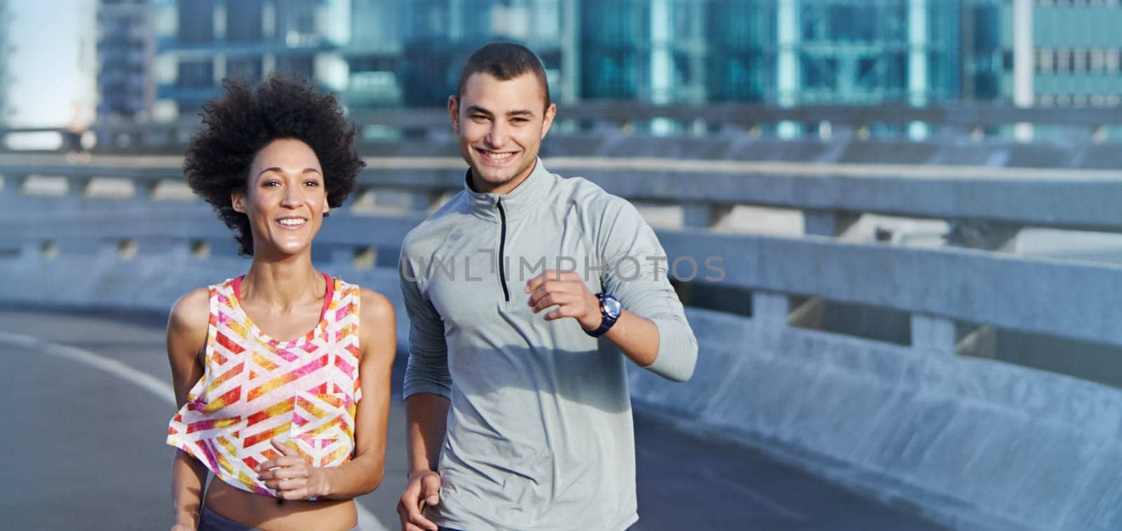 We love a good run. Portrait of two friends jogging together through the city streets