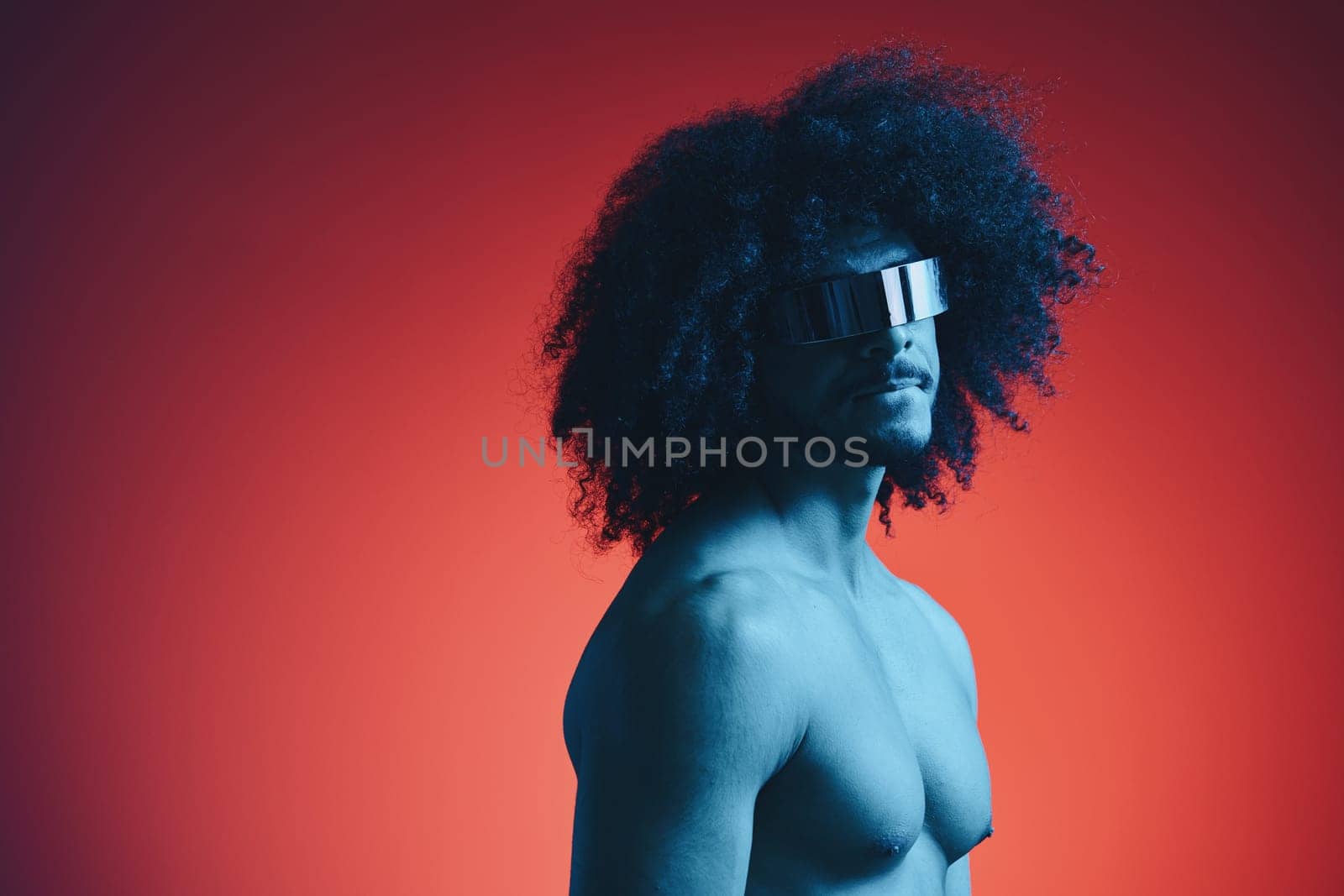 Portrait of fashion man with curly hair on red background with stylish glasses, multinational, colored light, black leather jacket trend, modern concept, sexy body. by SHOTPRIME
