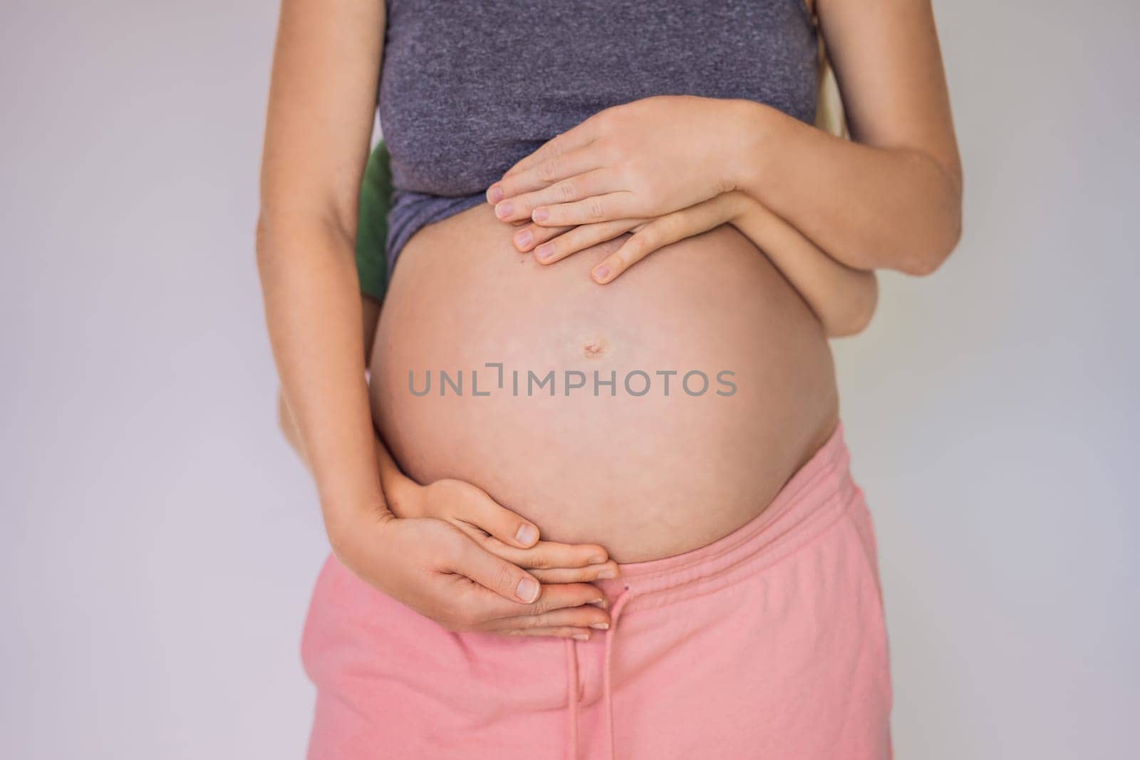 Young beautiful pregnant woman and eldest son. The cute boy put his hands on his mother's belly. Expecting a baby in the family concept. Preparing an older child for a younger one.