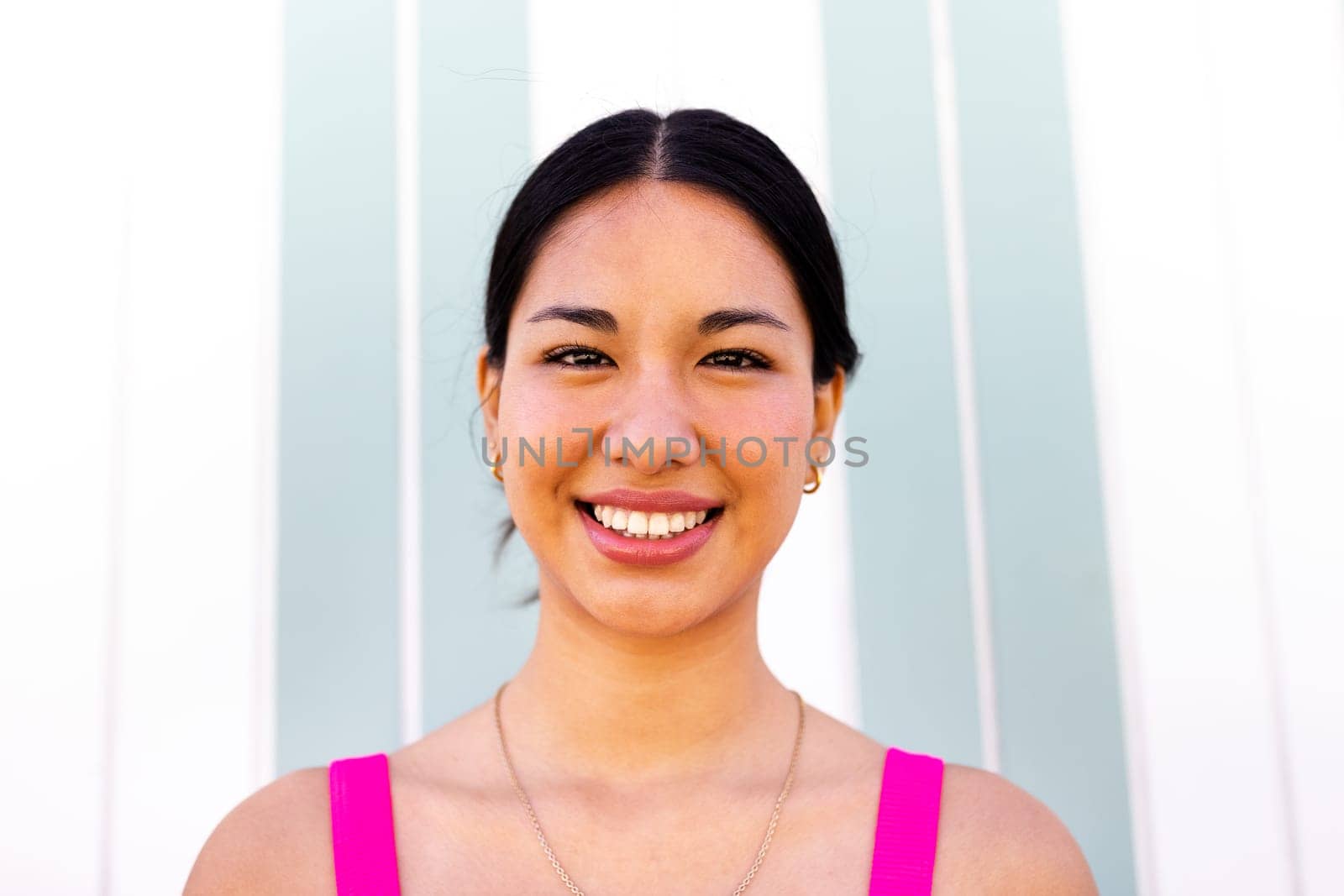 Headshot of young happy latina woman on summer vacation looking at camera. by Hoverstock