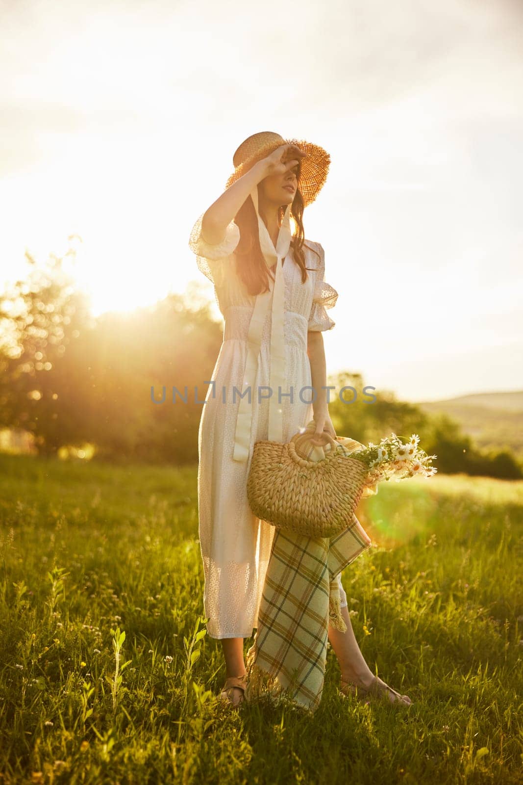 a woman in a light dress walks in the countryside in the rays of the setting sun. High quality photo