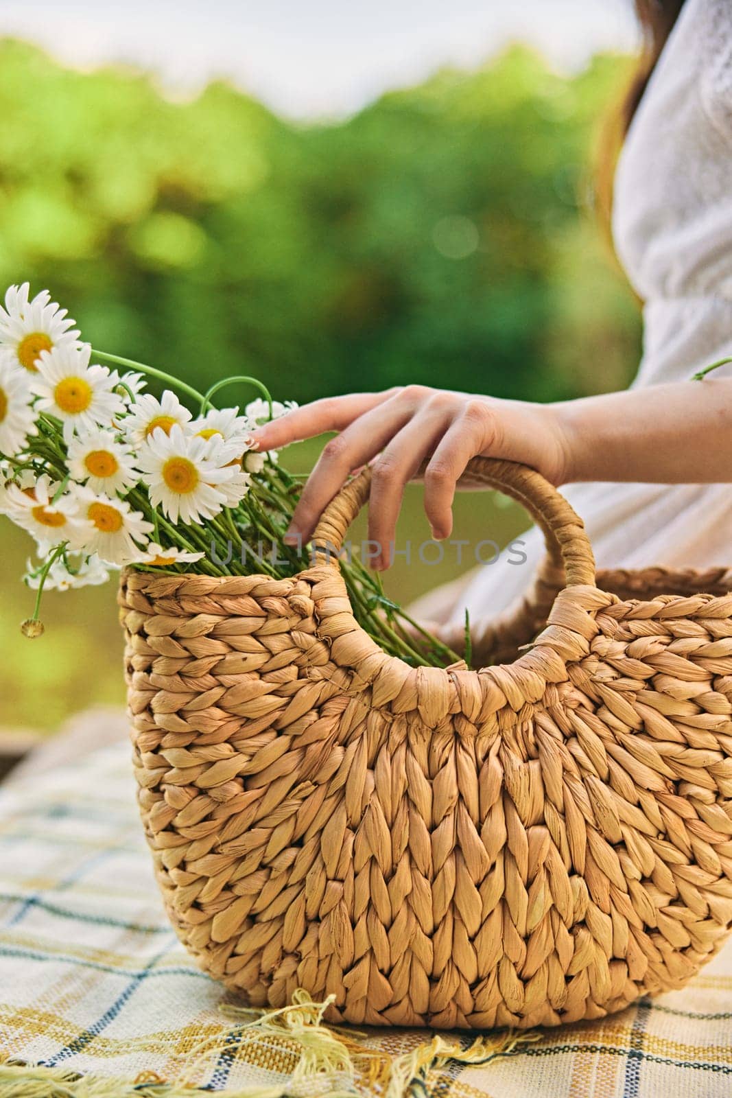 close vertical photo of a woman's hands with a wicker bag with daisies by Vichizh