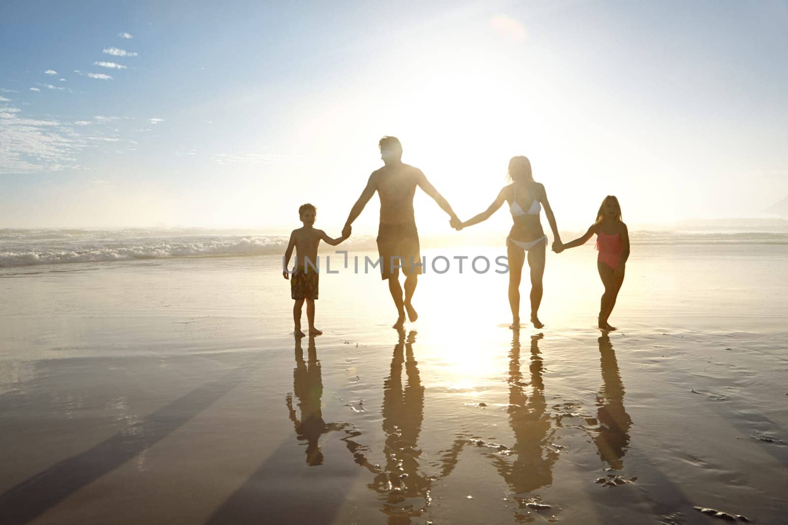 Summer silhouettes. a young family walking on a beach at sunset. by YuriArcurs