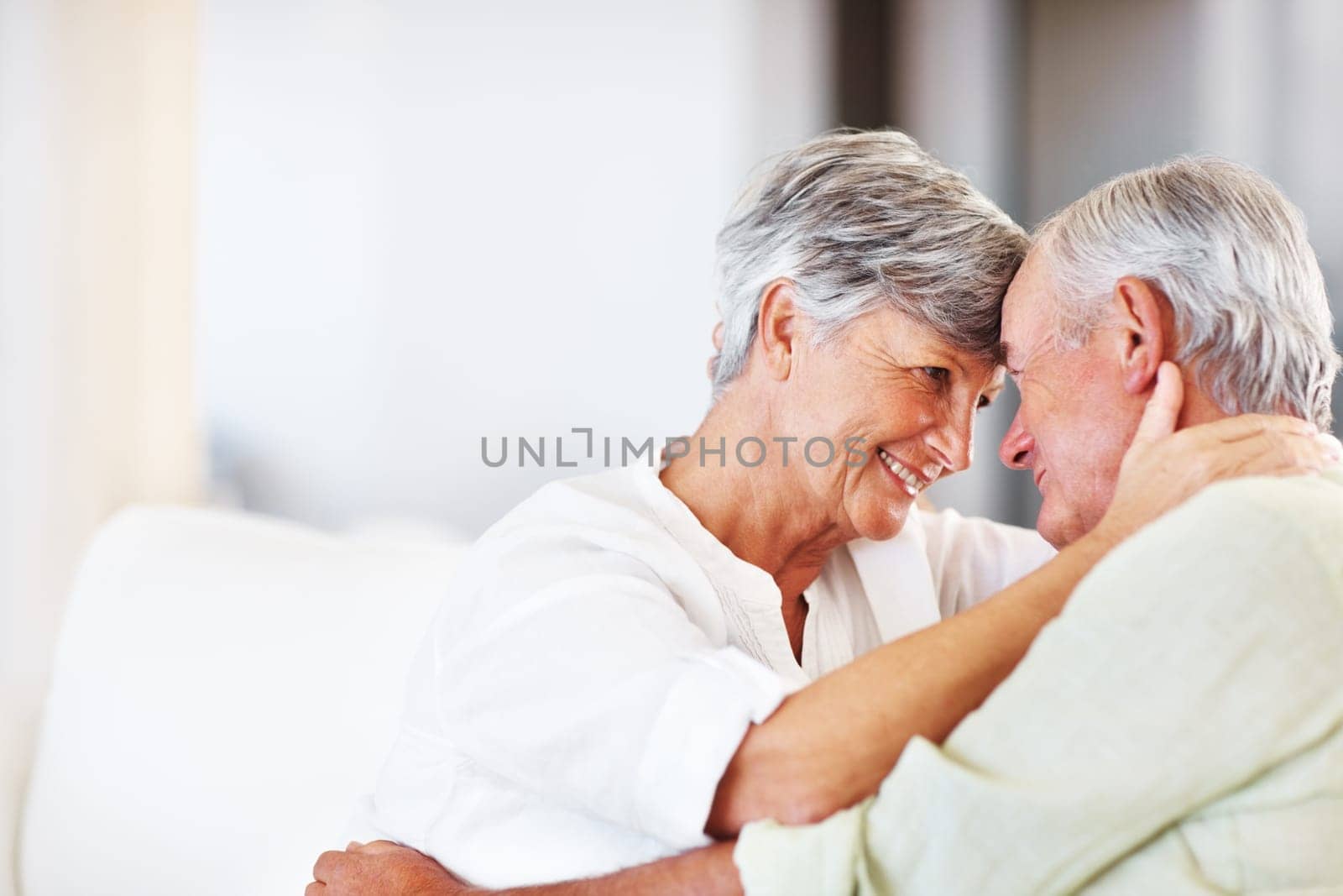 Romantic couple at home. Romantic mature couple smiling head to head while sitting on couch. by YuriArcurs