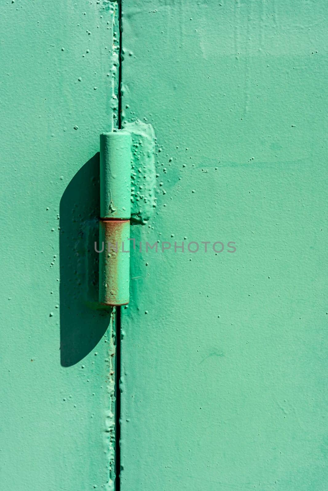 Metal hinge of the garage door. Powerful door hinge. Old iron door hinges. vertical photo