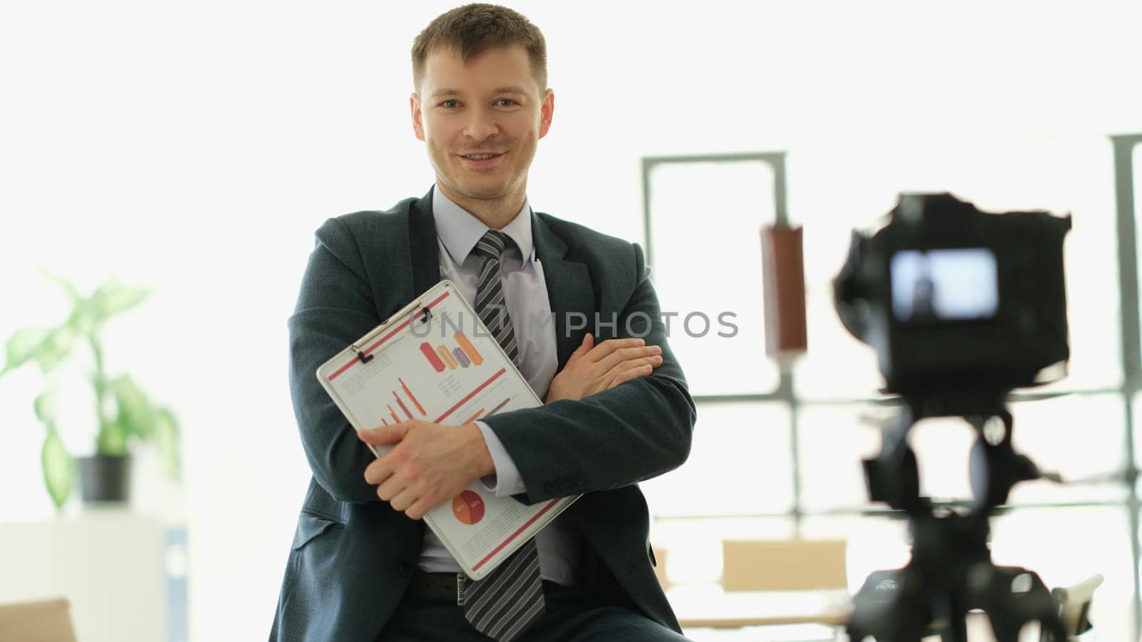 Male business coach standing in front of camera with documents in hands. School of business online concept