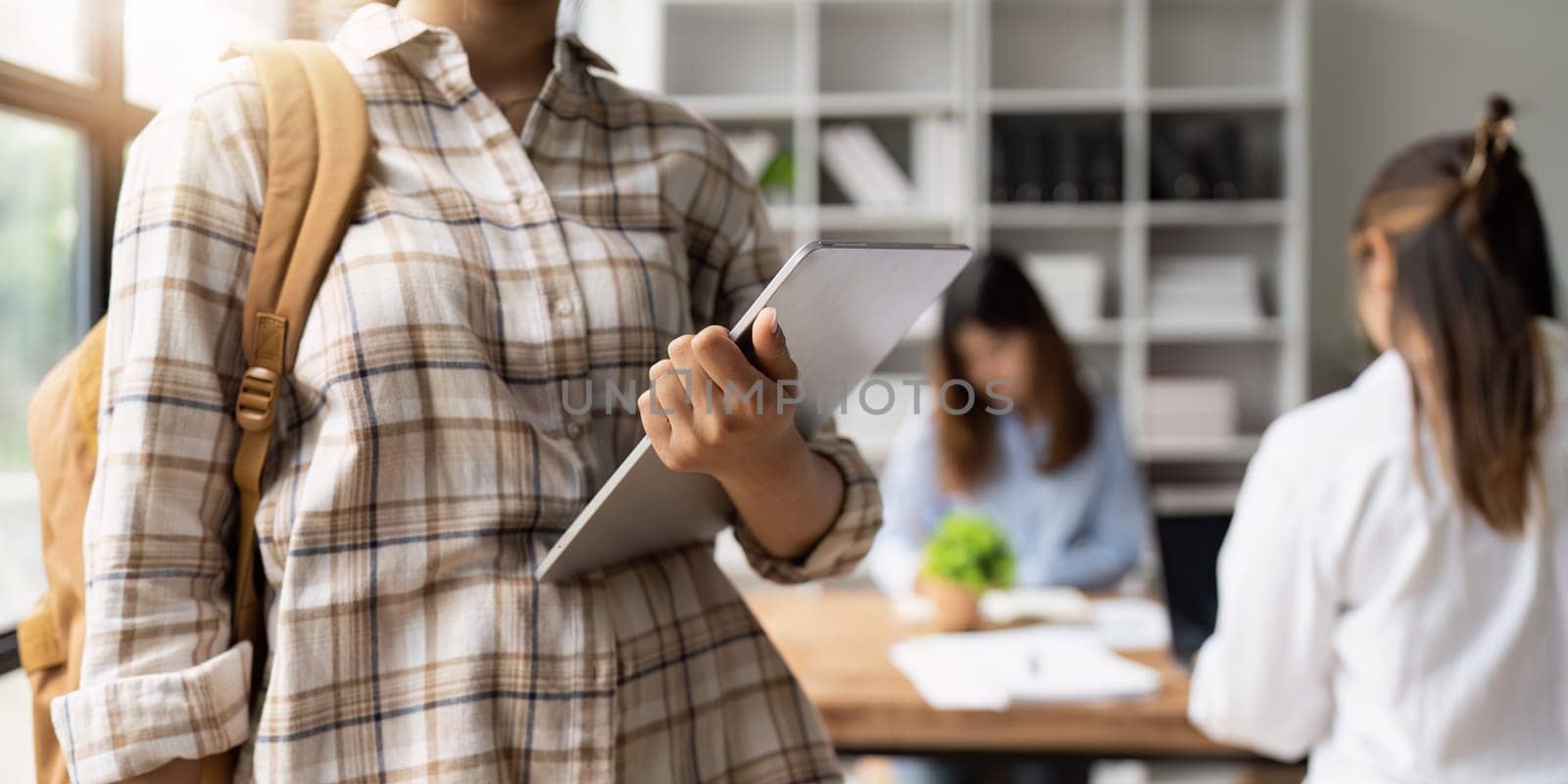 Close up of Young student with backpack carrying digital tablet in college. Student working at background. education, back to school concept.