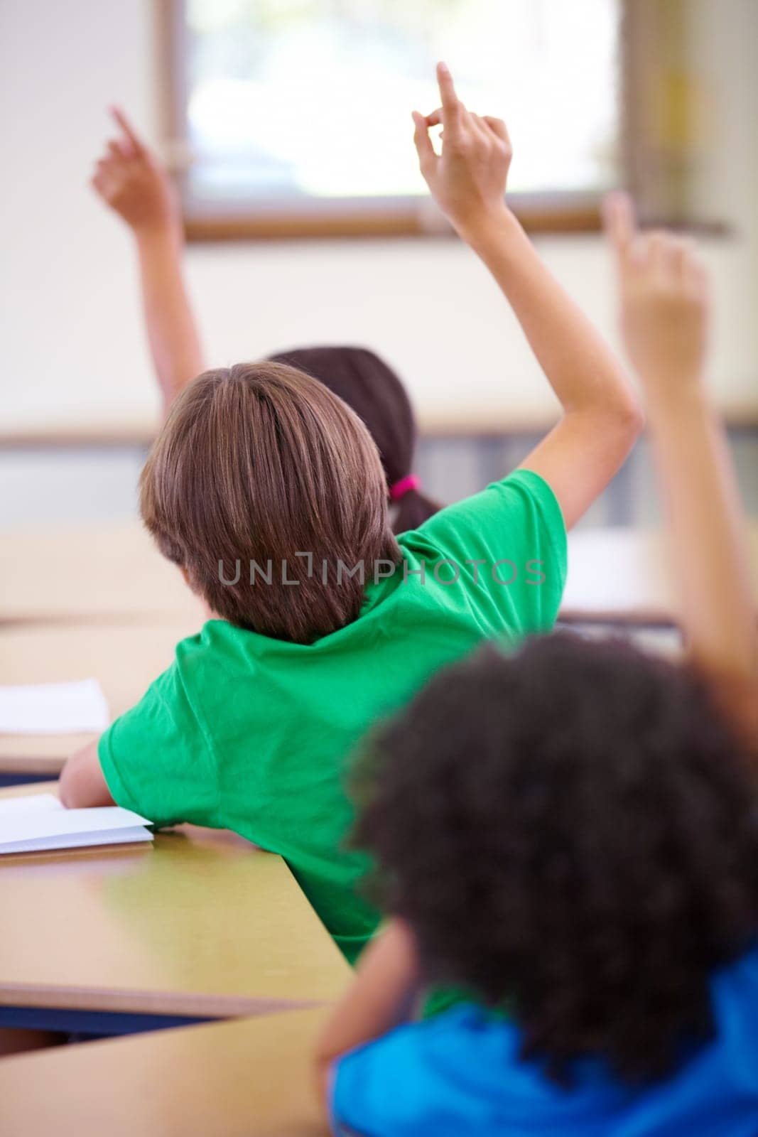 Classroom, raise hands and children rear for questions, education and language learning or quiz in school. Young group, kindergarten or clever kids with arms up for students support, ideas or answer by YuriArcurs