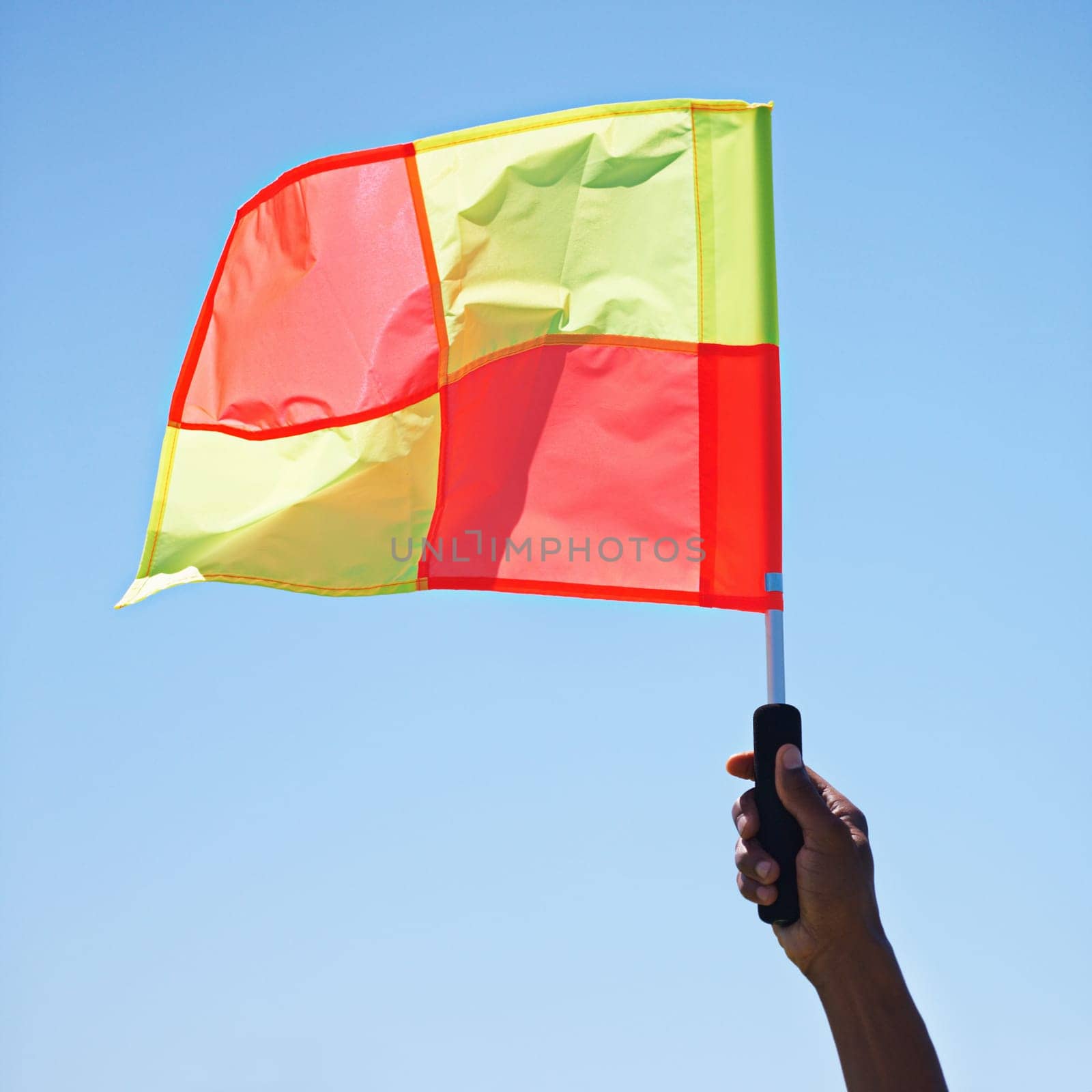 Flag, stop and soccer referee in football match or game wave a foul sign during sport training or workout. Hand, sports and person or assistant official raise or signal mistake in sky background by YuriArcurs