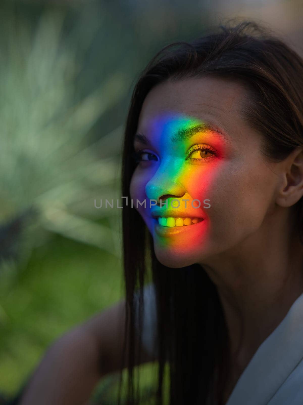 Portrait of caucasian woman with rainbow beam on her face outdoors