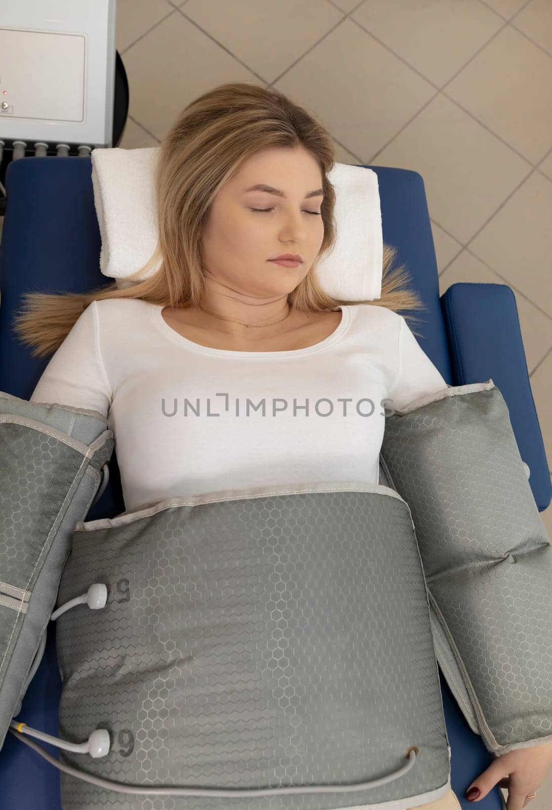 Top view pressure therapy procedure. Woman lying in massaging suit in hospital, treatment of varicose veins, edema, lymphatic drainage,weight loss. Relaxation,cure. Pressotherapy concept Vertical by netatsi