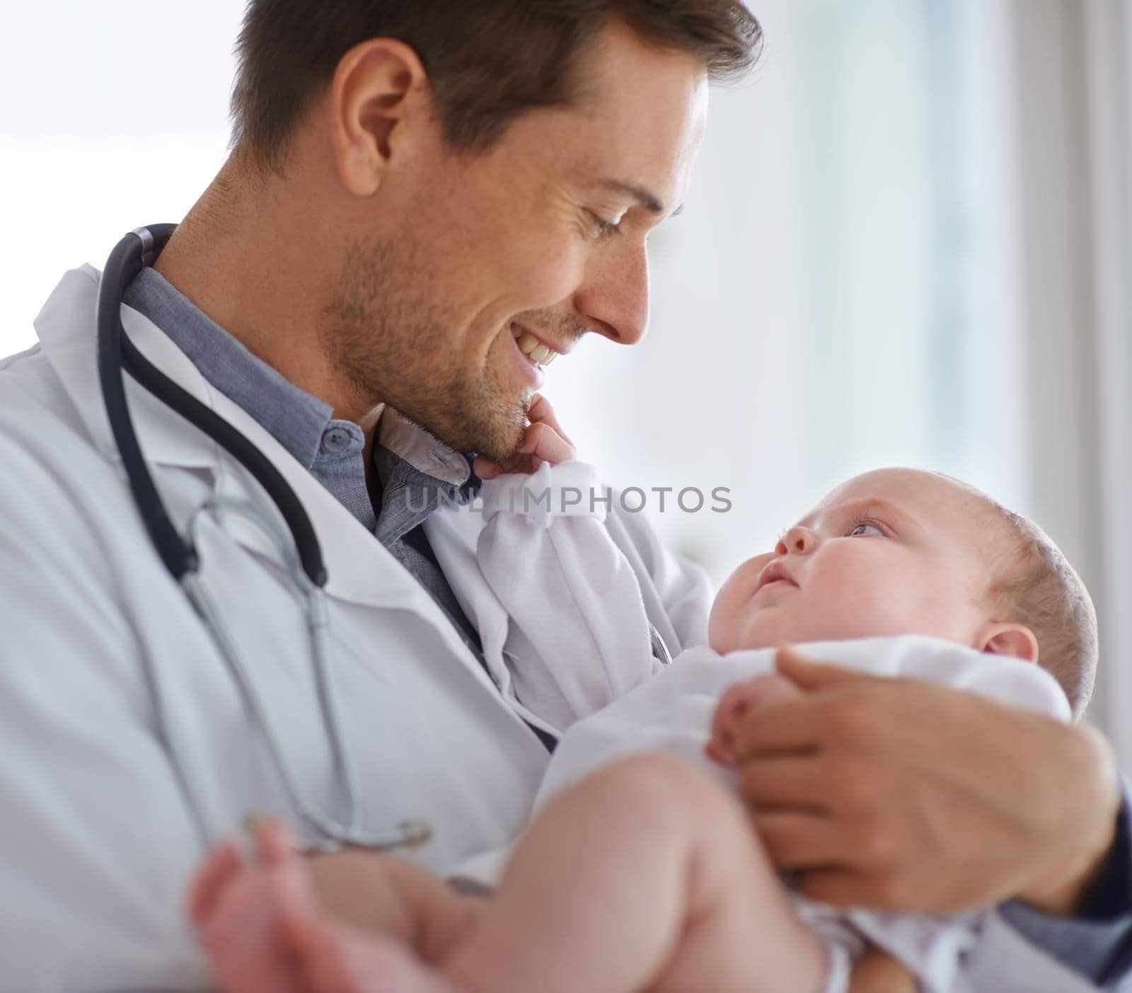 Happy male doctor, pediatrician and holding baby for hospital assessment, medical support and growth. Pediatrics, physician and carrying newborn kid in clinic, healthcare service and helping children by YuriArcurs