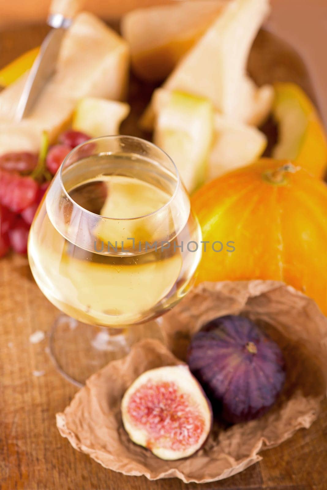 Cheese plate served with grapes, melon, figs, crackers, honey, nuts and white wine on a wooden table by aprilphoto