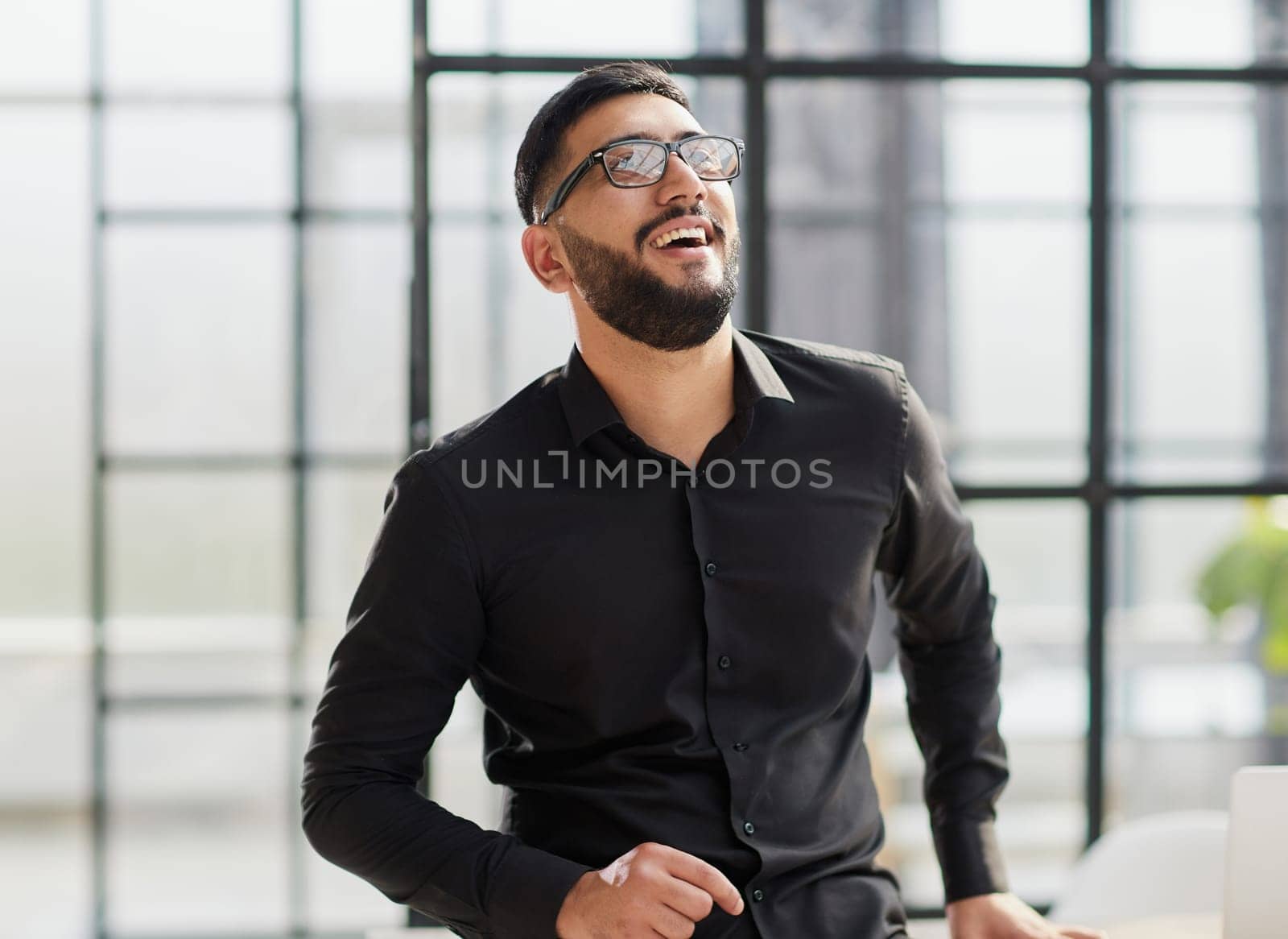young businessman smiling in the office with his arms crossed