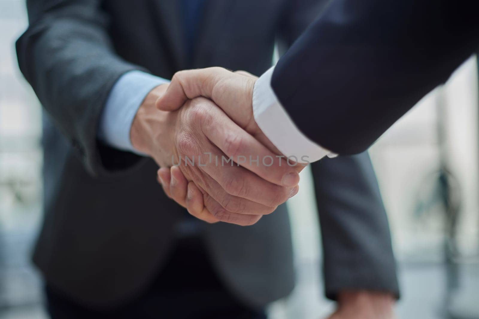 Two diverse professional business men executive leaders shaking hands at office meeting