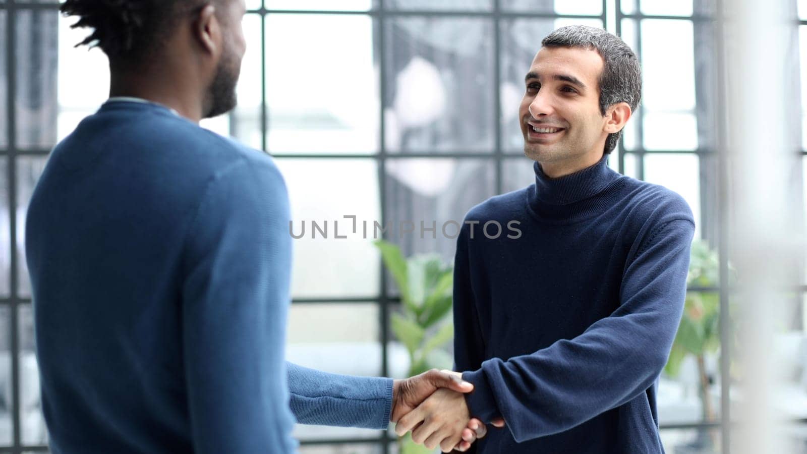 Diverse male colleagues in modern office corridor, young african american and caucasian business people discussing common project work, meeting in company work