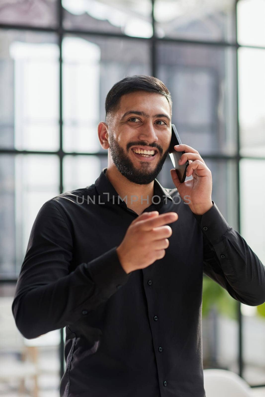 young man in a black shirt talking on the phone in the office