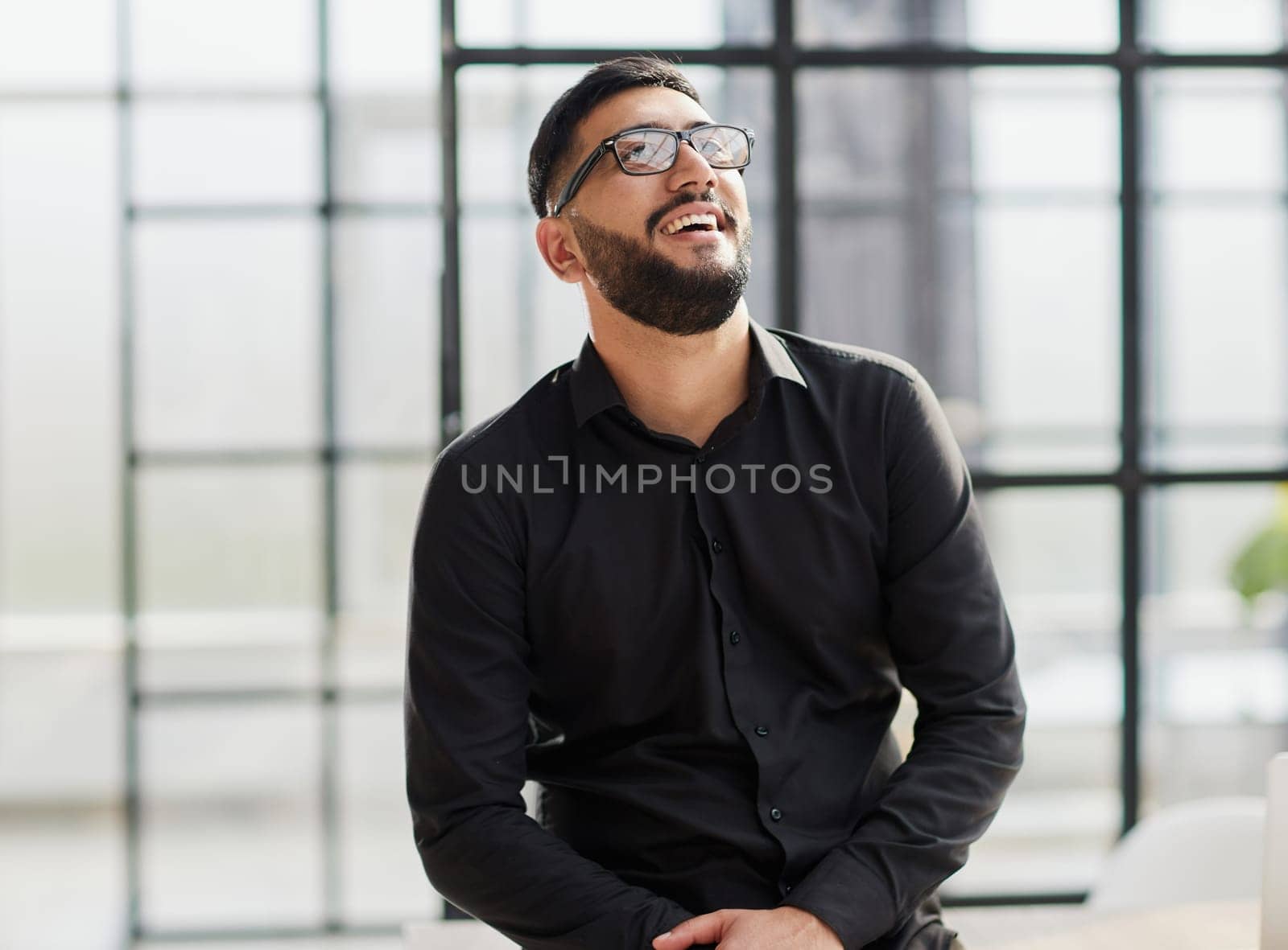 young businessman smiling in the office with his arms crossed