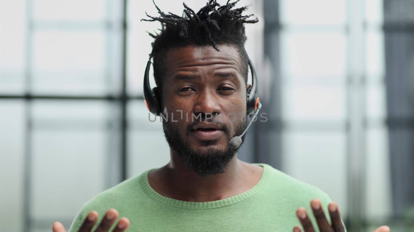 Operator of hot line. Portrait of cheerful african customer service representative with headset in call center, empty space