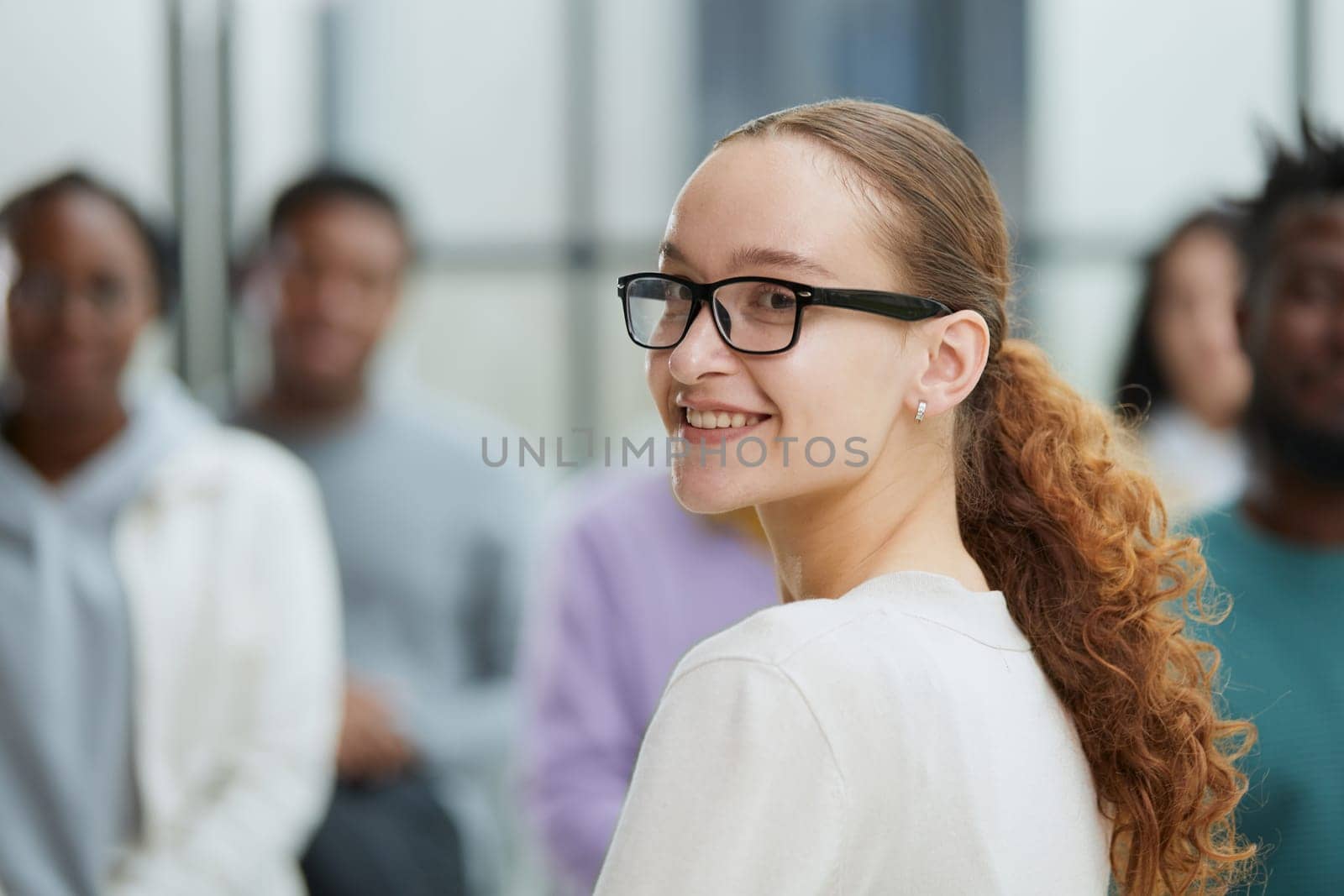 Business woman sitting on a chair with her staff in the background by Prosto