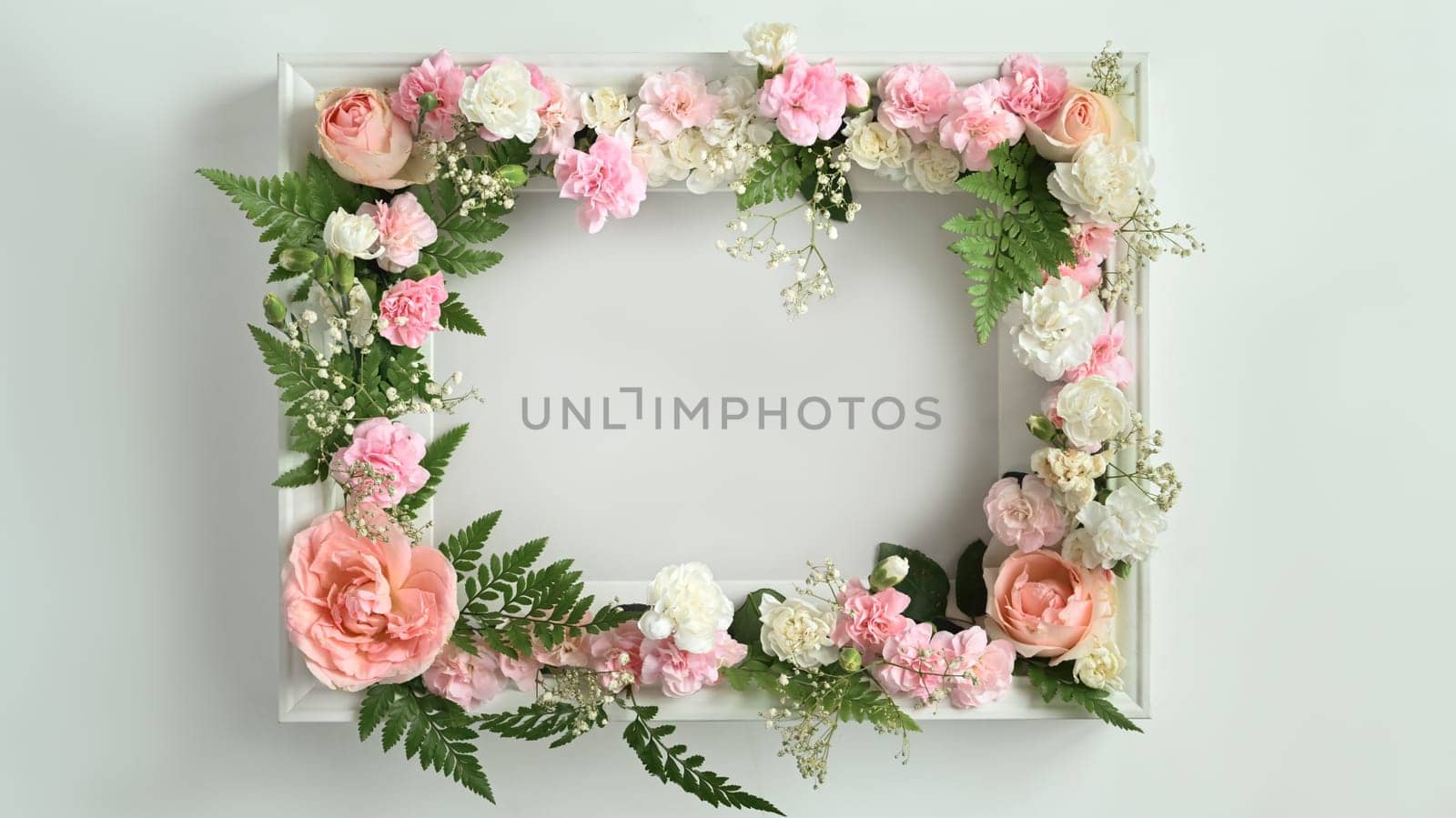 Round frame made of pink rose, carnation and fern leaves on white background. Spring floral background, copy space by prathanchorruangsak