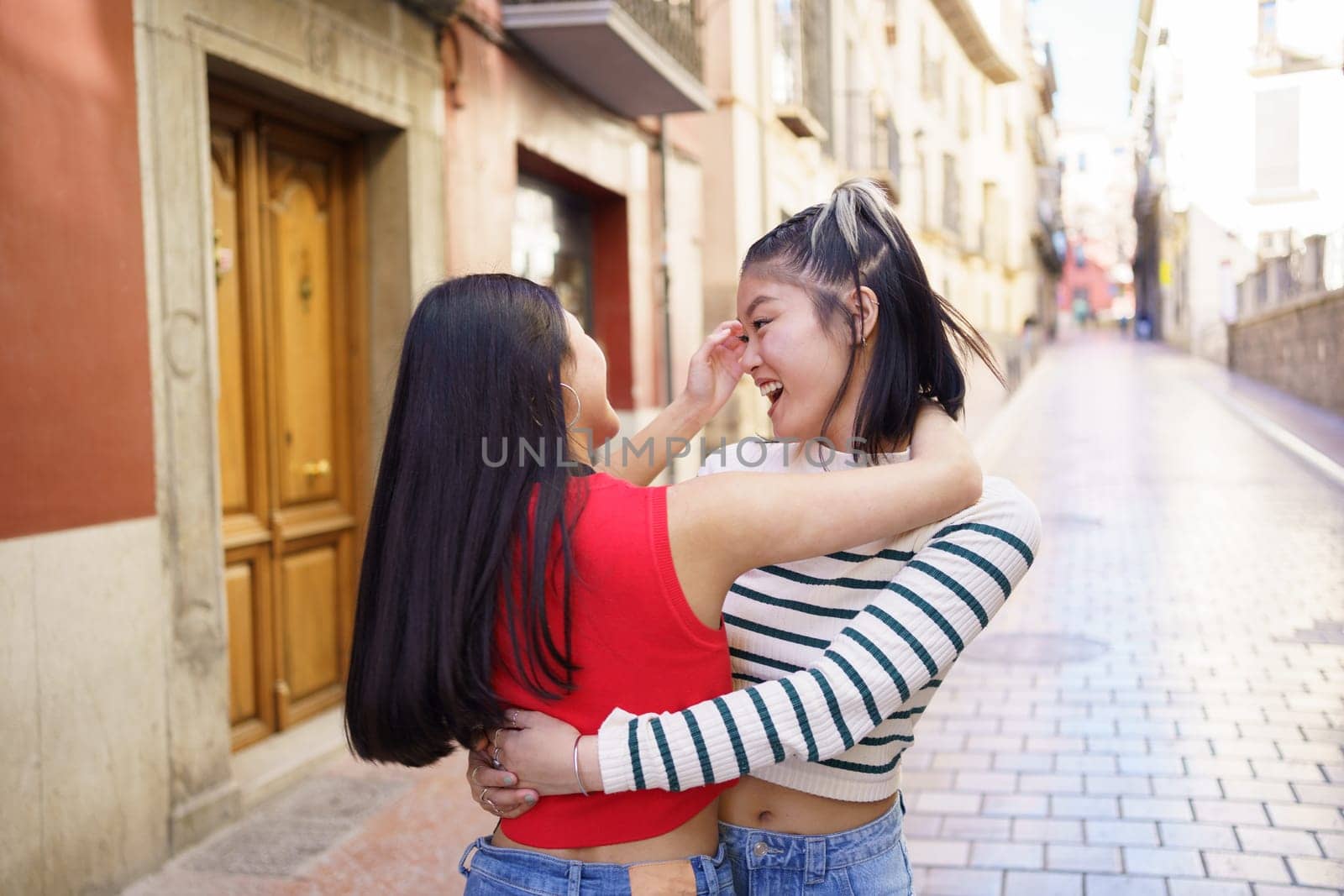 Happy Asian women hugging on street by javiindy
