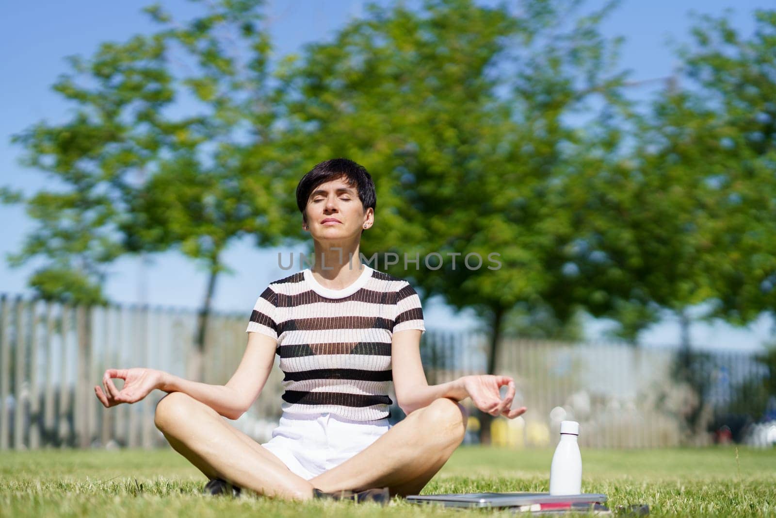 Calm woman meditating in park with closed eyes by javiindy