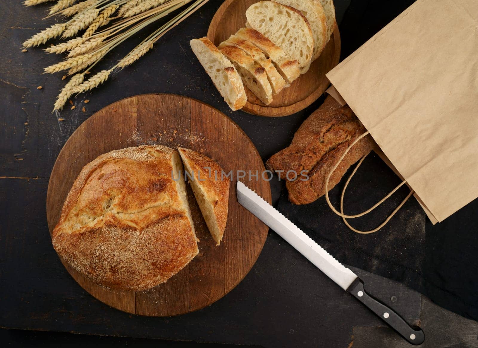 hopped grain bread put on kitchen wood plate with knife for cut. Fresh bread on table close-up. Fresh bread on the kitchen table. The healthy eating and traditional bakery concept. Top viev. by aprilphoto