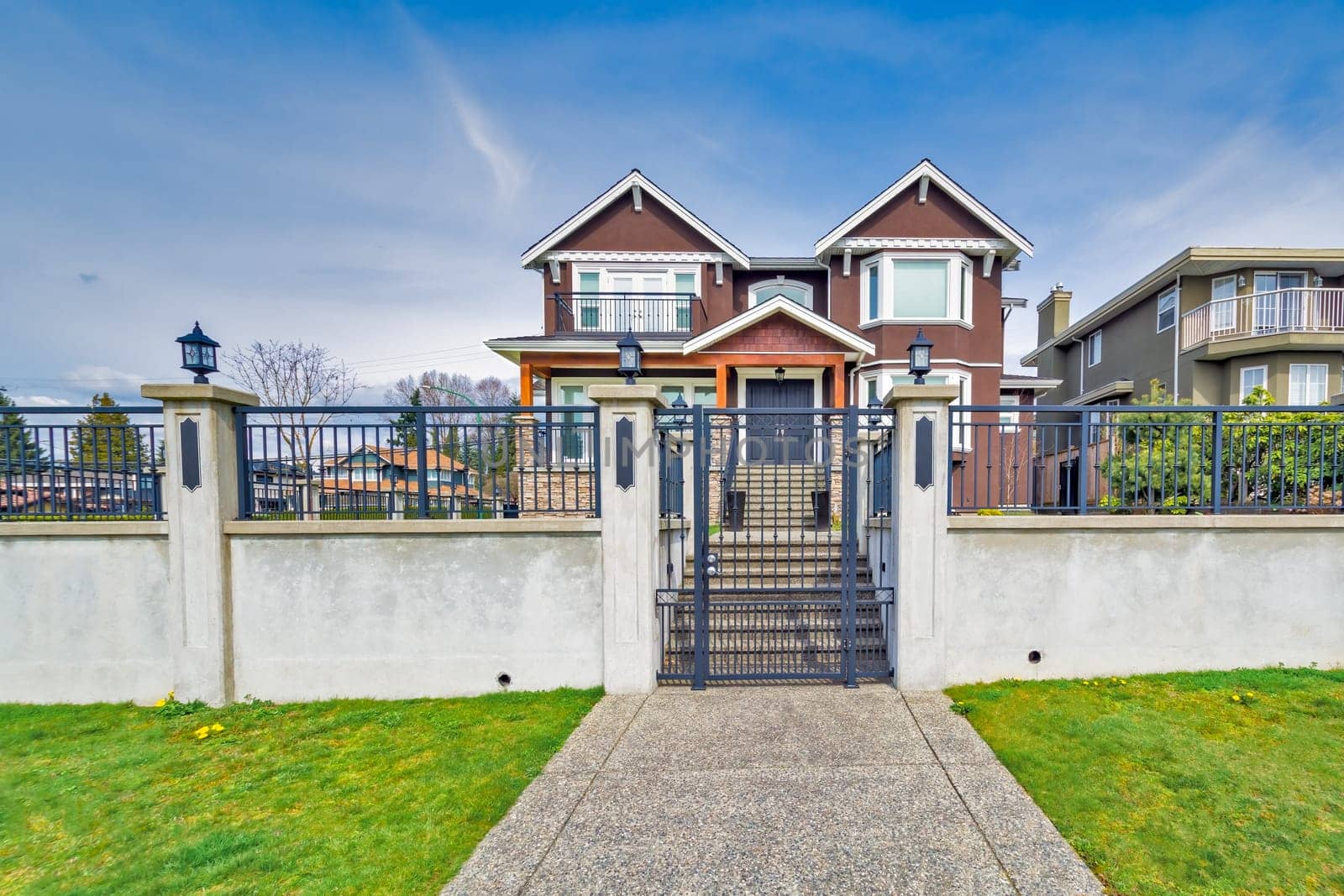 Luxury residential houses with landscaped front yard on land terrace. Big family house on blue sky background