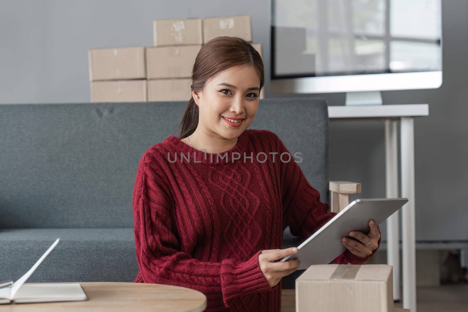 Asian Women business owner working at home with packing box on workplace - online shopping SME entrepreneur or online selling concept.