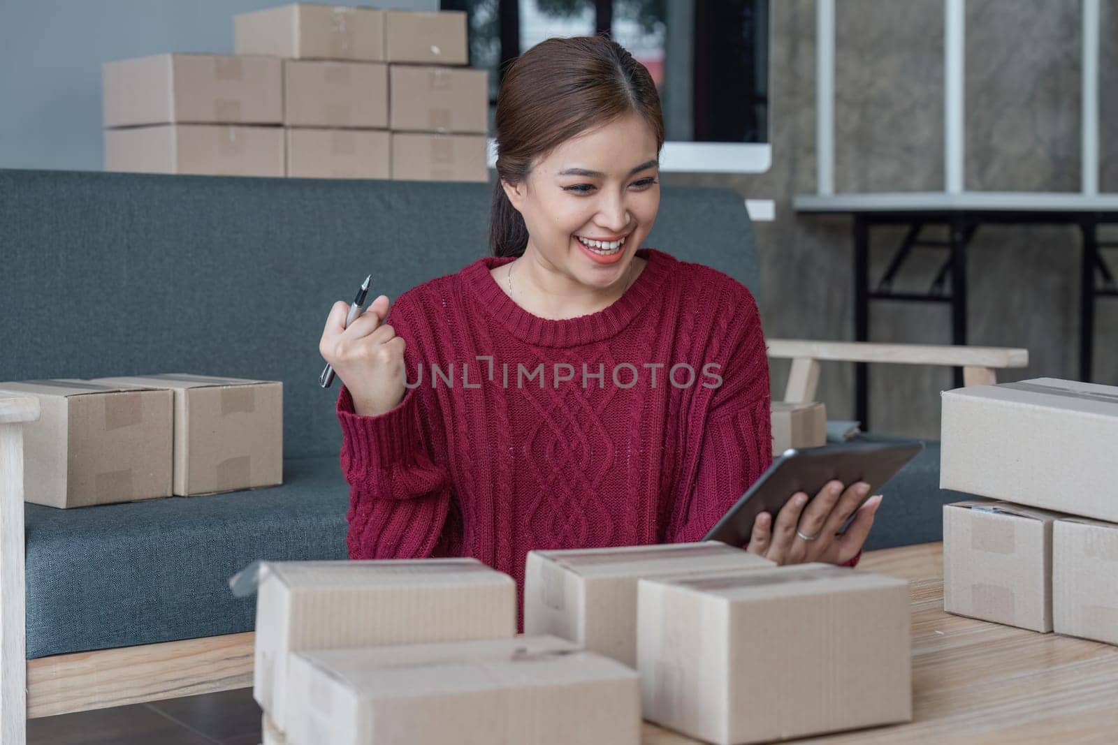 Happy young Asian woman entrepreneur, Smile for sales success after checking order from online shopping store in a tablet at home office, Concept of merchant business online and eCommerce.