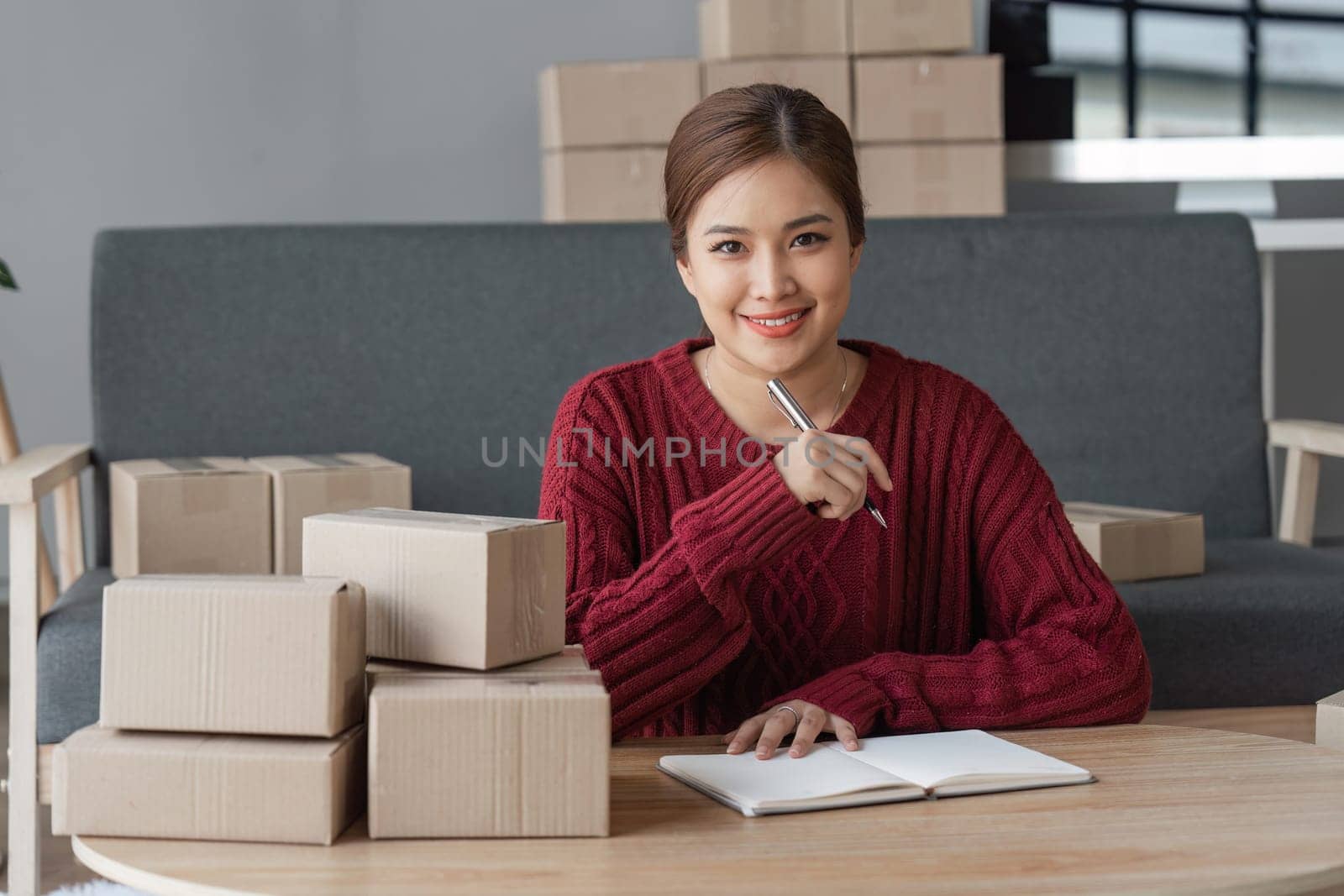 Asian Women business owner working at home with packing box on workplace - online shopping SME entrepreneur or online selling concept.