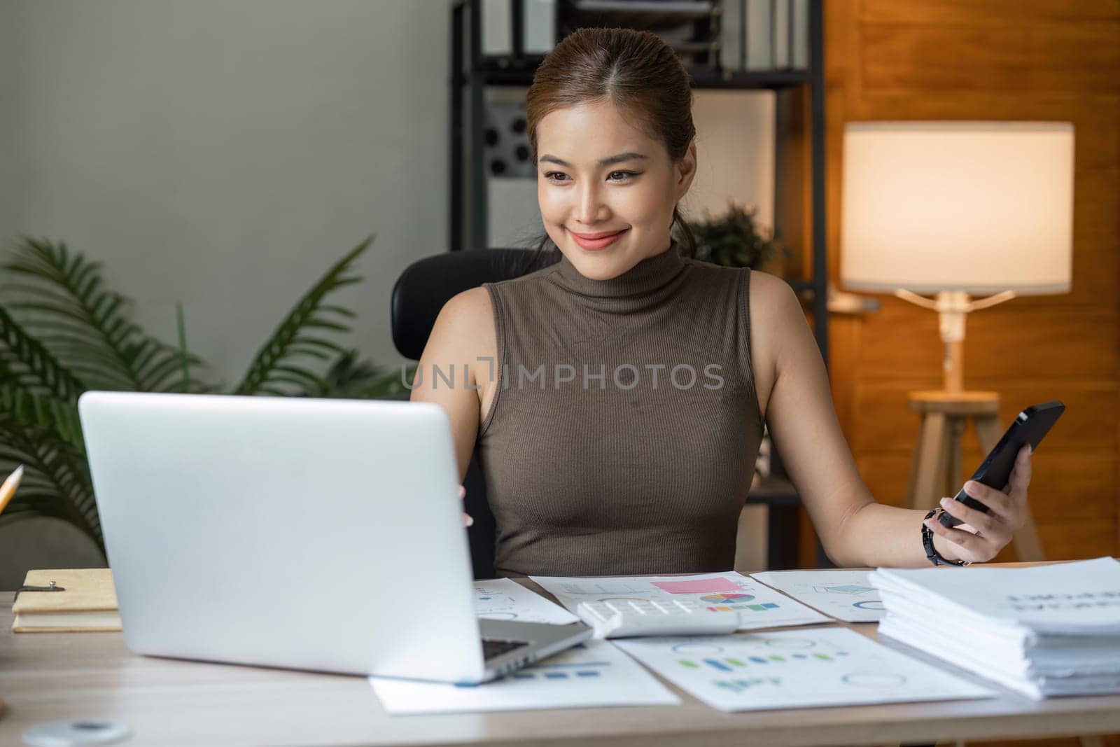 Asian businesswoman in home happy and cheerful during using smartphone and working.