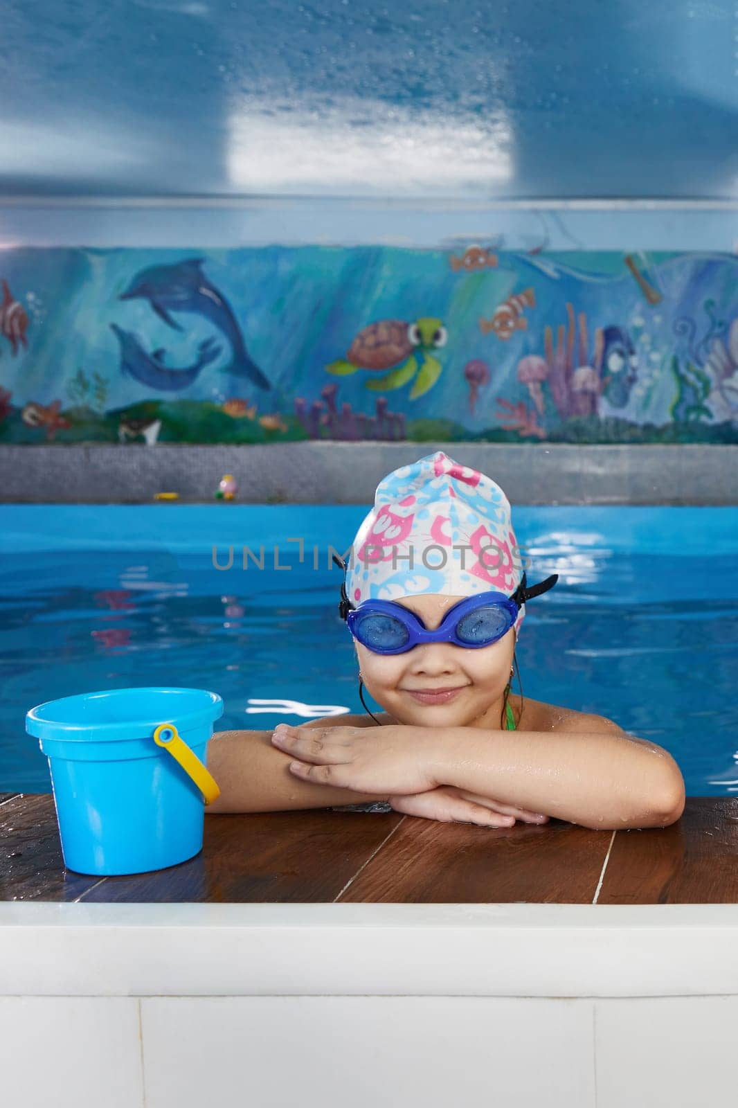 Kids taking a break during swimming class in indoor pool by Mariakray
