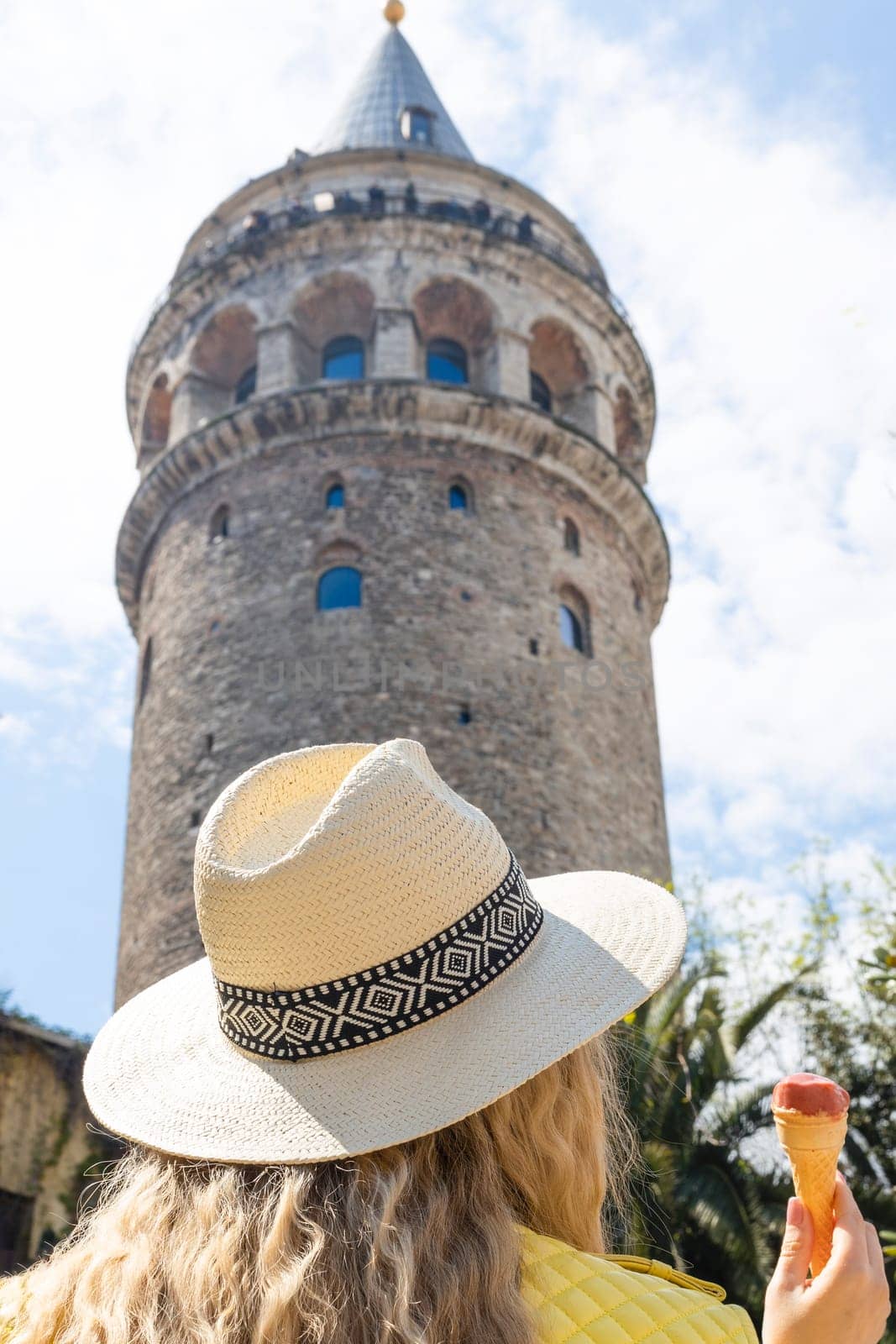 Beautiful young tourist girl in fashionable clothes poses with view of landmark Galata tower in Beyoglu,Istanbul,Turkey.Traveler Concept image by malyshph