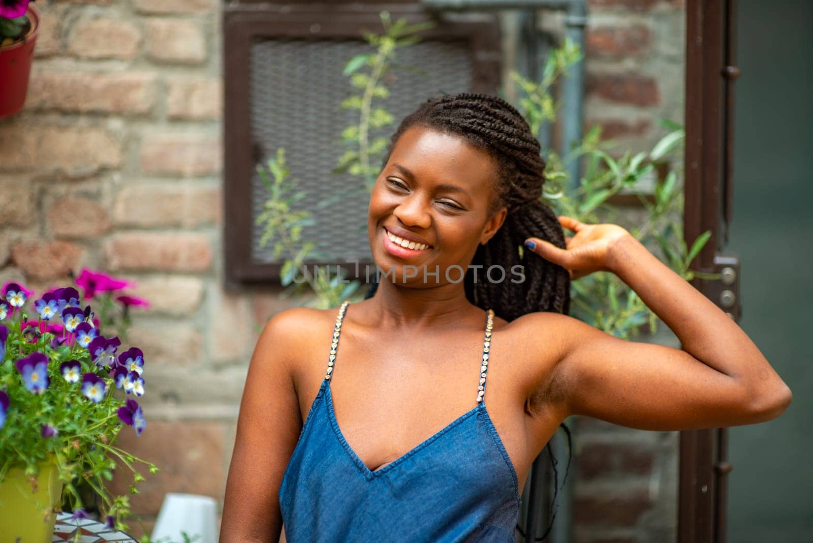 relaxed young black woman sitting. Stylish model. Braid dreadlock hairstyle. Confident African female in selective focus outdoors, fashion style, happiness concept. Outdoors.