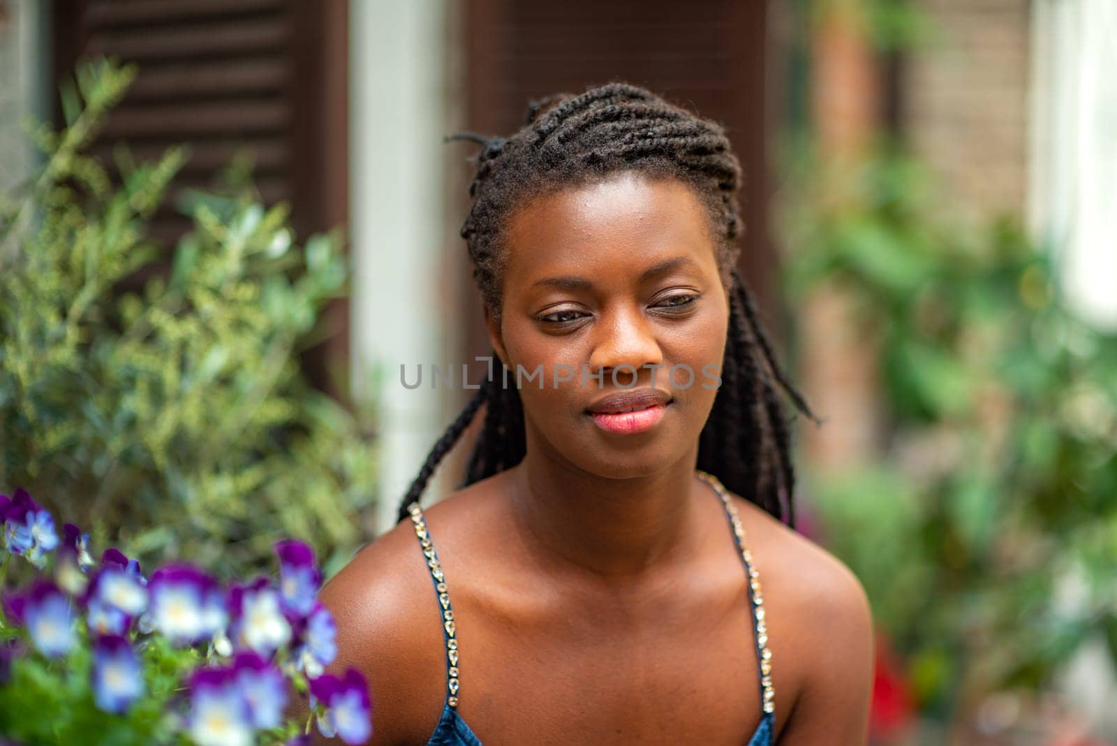 relaxed young black woman sitting. Stylish model. Braid dreadlock hairstyle. Confident African female in selective focus outdoors, fashion style, happiness concept. Outdoors.