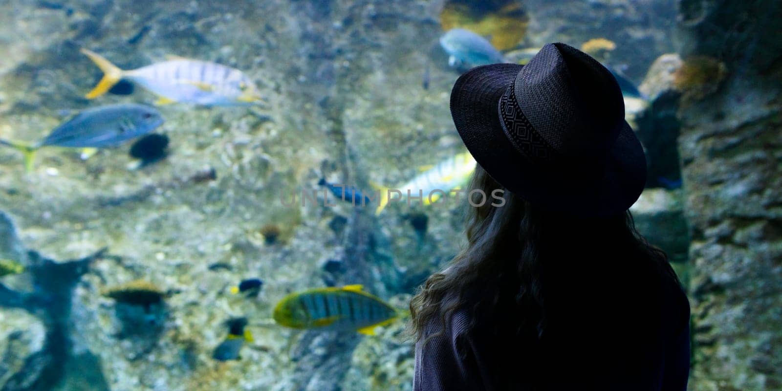 A young woman touches a stingray fish in an oceanarium tunnel.