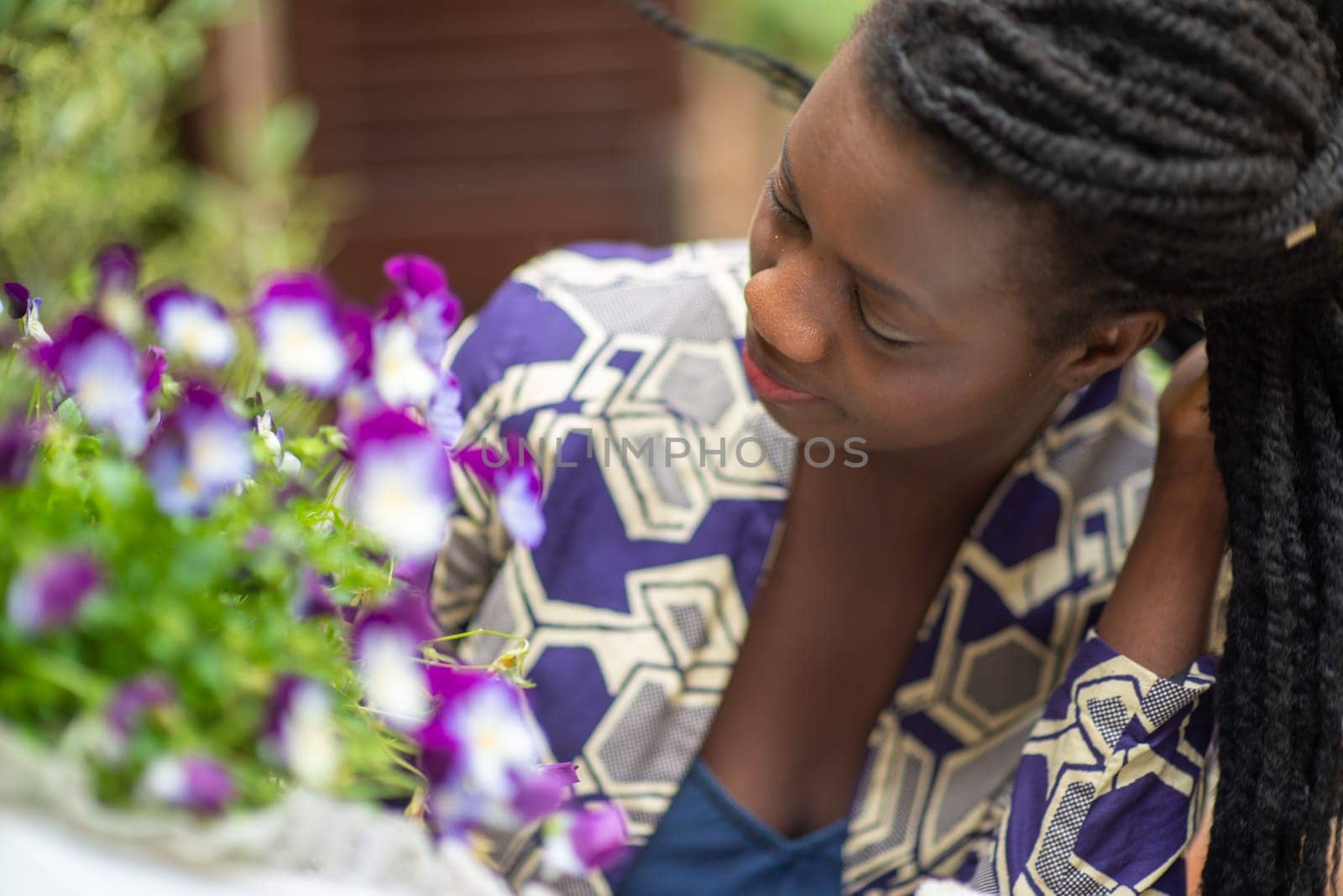 relaxed young black woman sitting. Stylish model. Braid dreadlock hairstyle. Confident African female in selective focus outdoors, fashion style, happiness concept. Outdoors.