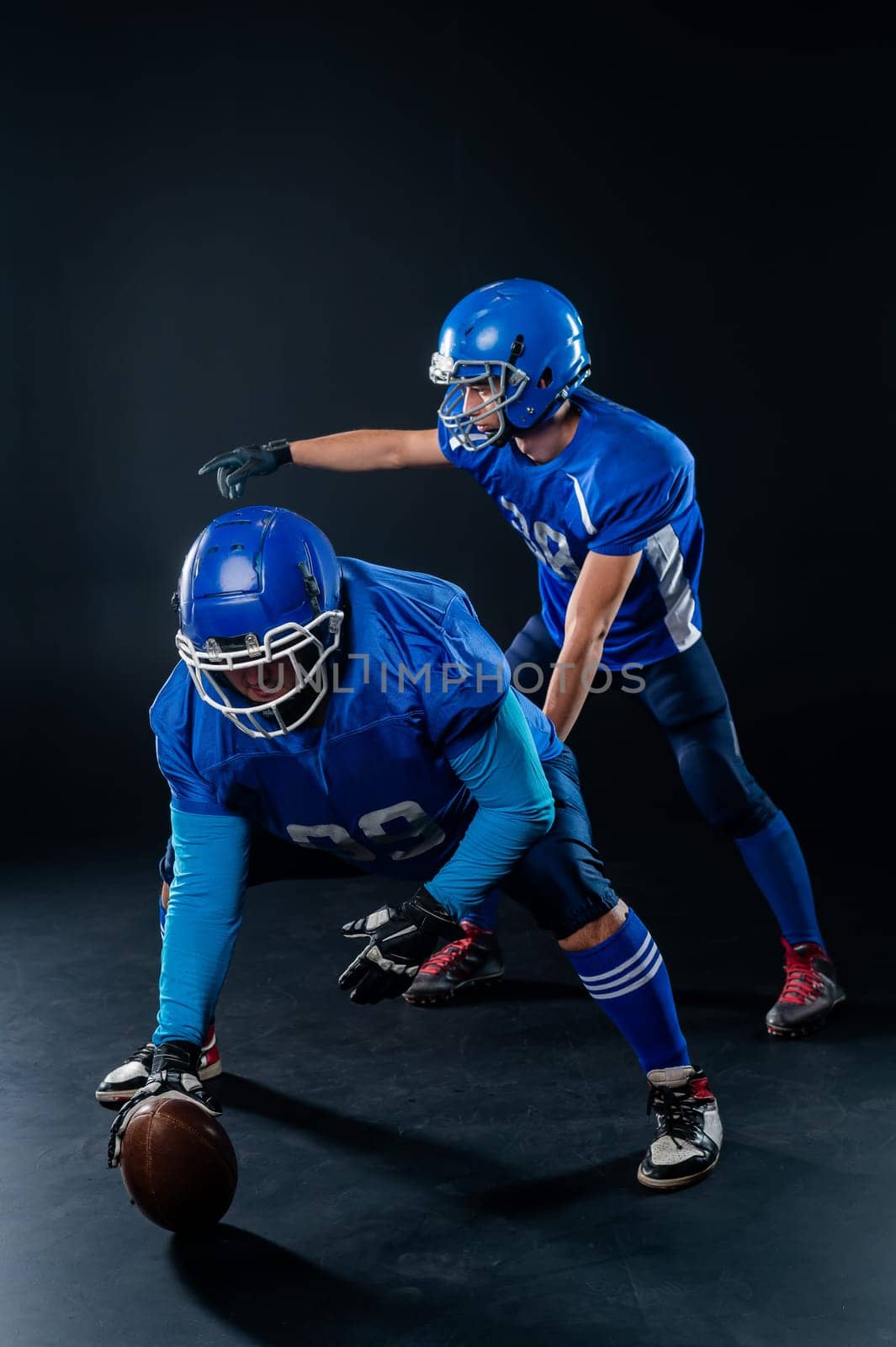 Two American football players are ready to start the game on a black background. by mrwed54