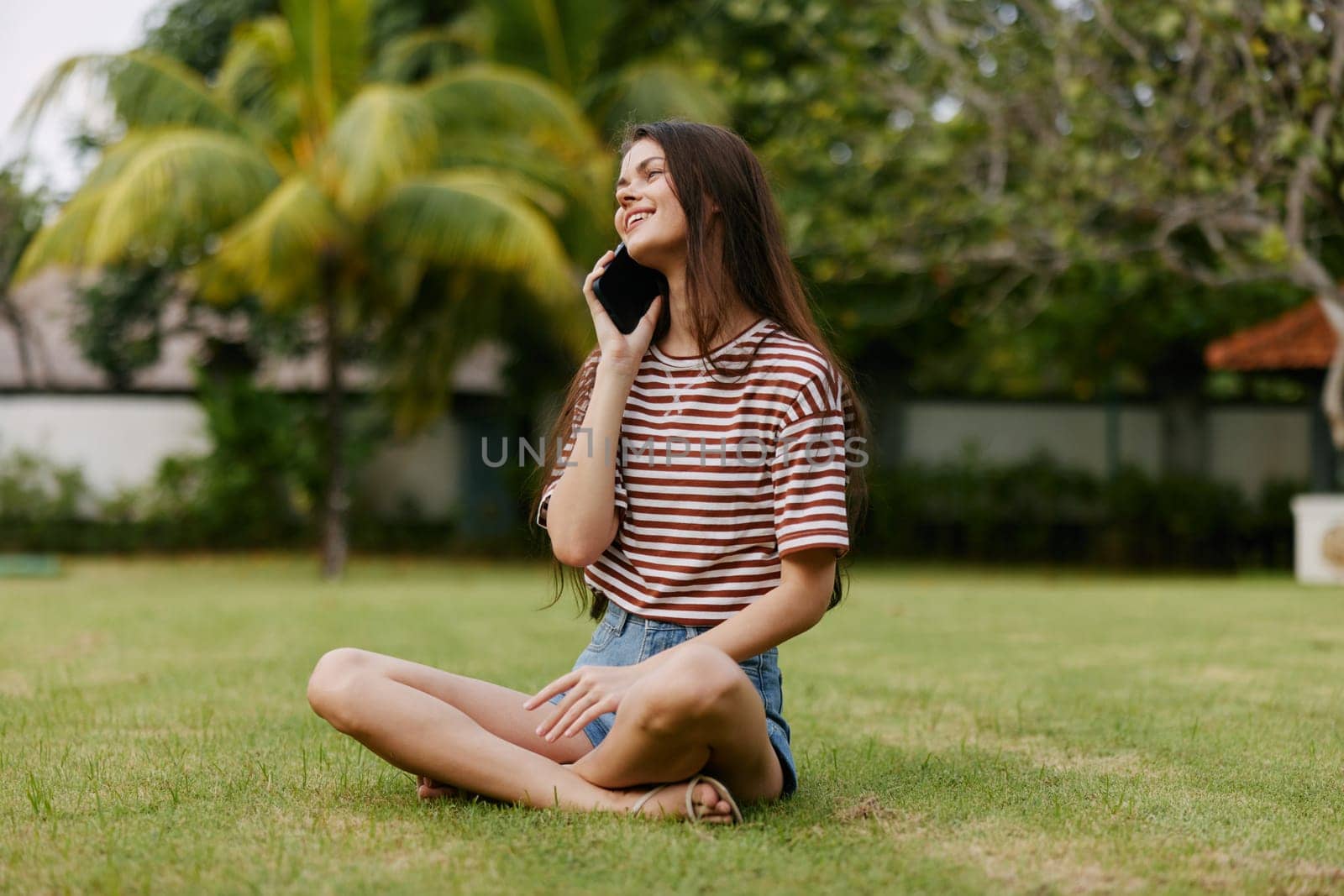 lifestyle woman seasonal tree blogger smiling person shirt palm caucasian network girl using smile spring phone happy grass park nature outdoor striped