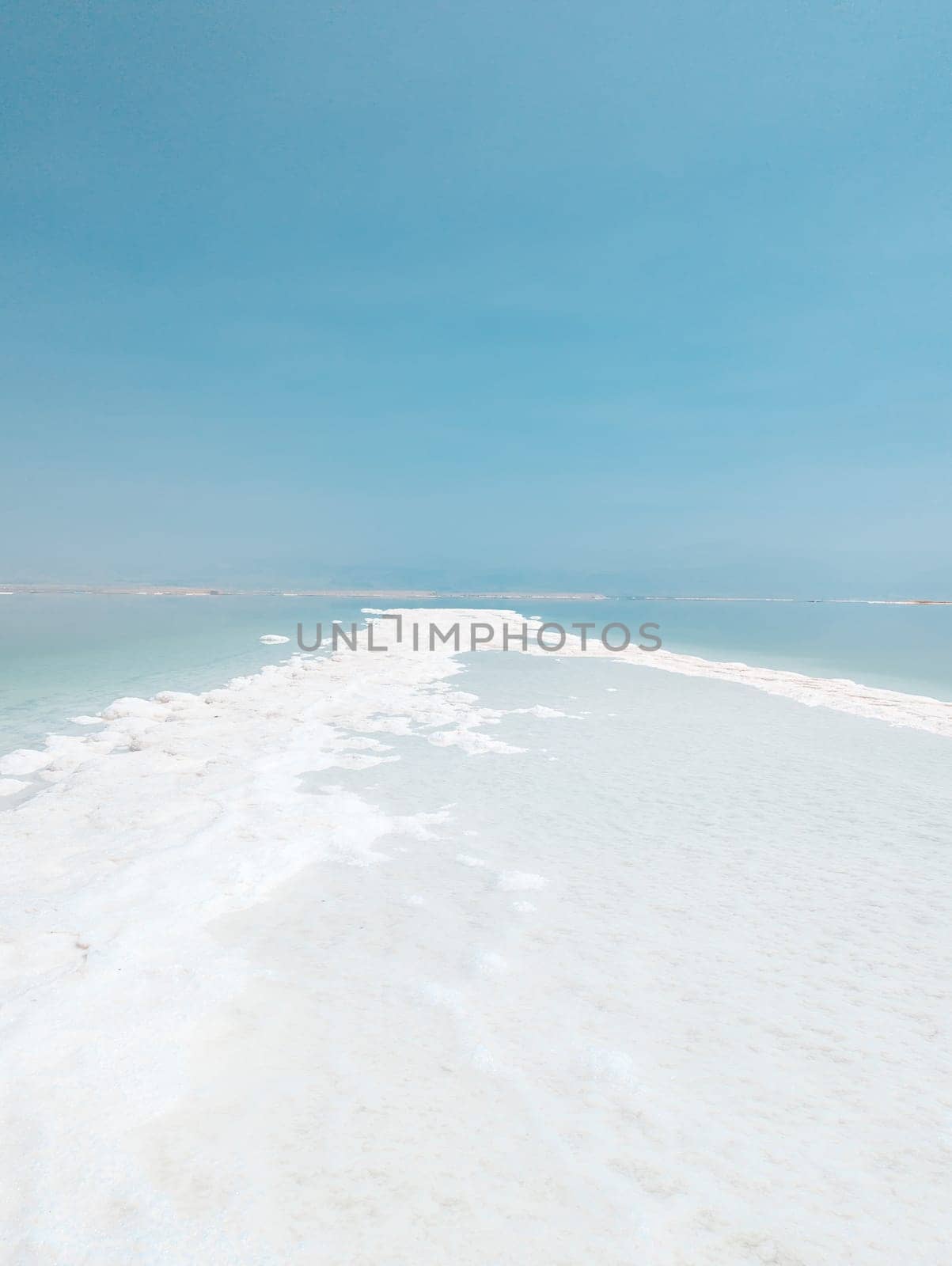 Landscape view on Dead Sea salt crystals formations, clear cyan green calm water at Ein Bokek beach, Israel