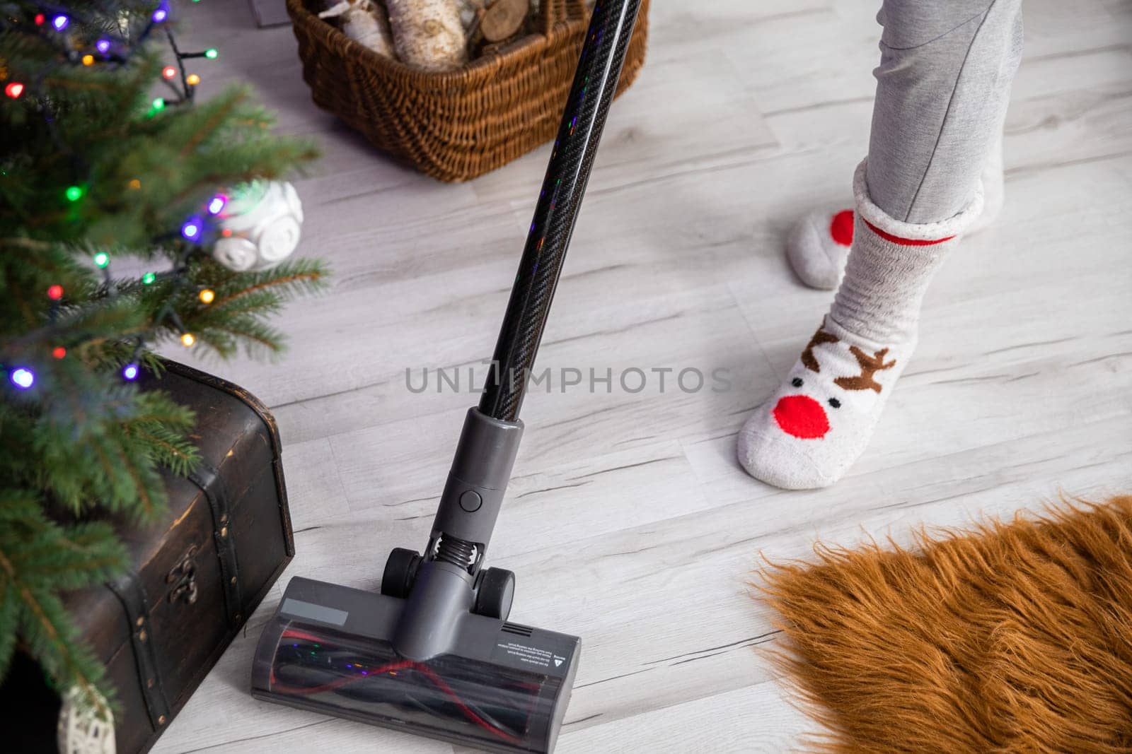 By the Christmas tree is cleaned with a vacuum cleaner. Home preparations for the celebration of Christmas.
