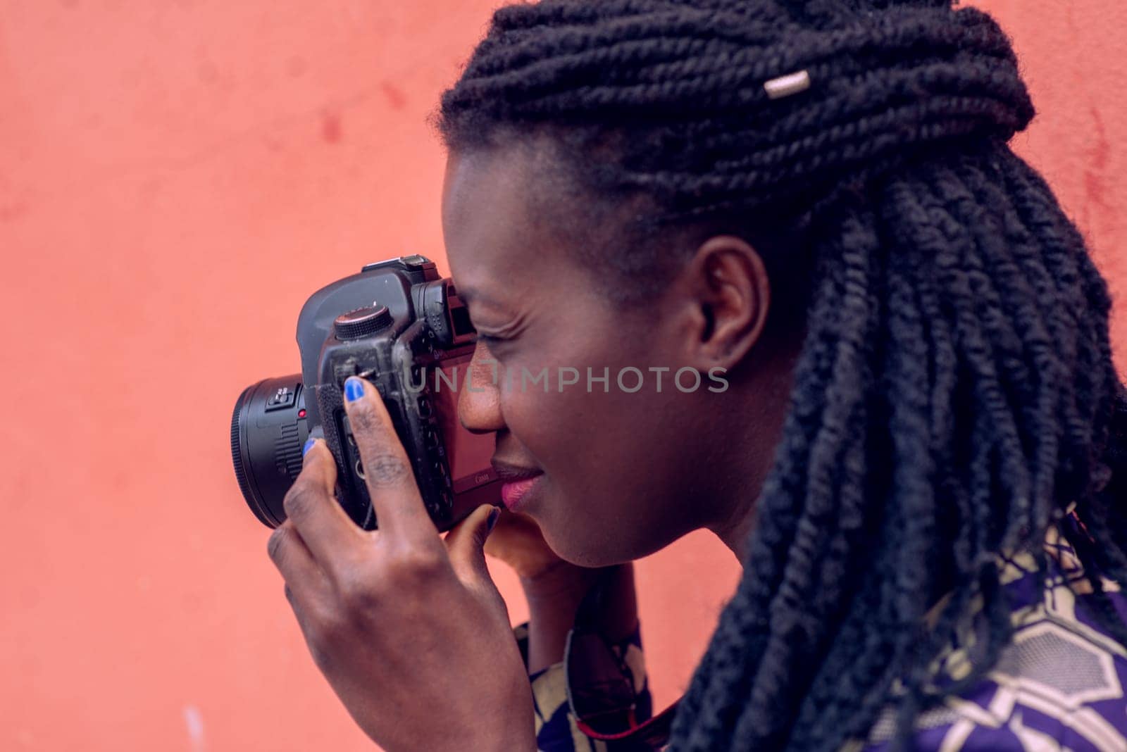 Close up portrait of beautiful young woman with braid hairstyle concentrated while making a photograph with reflex camera over a wall outdoors