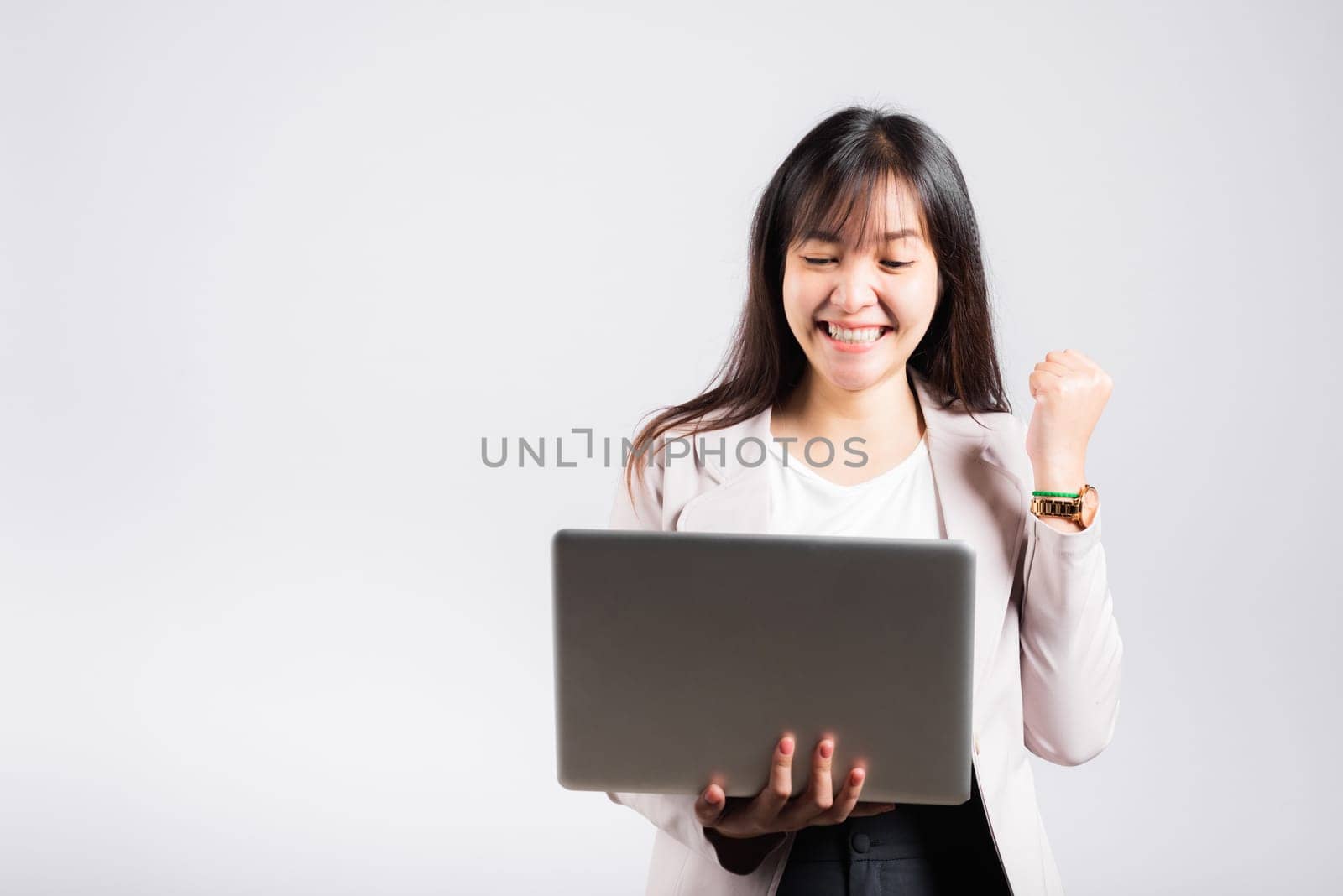 Woman smiling confident holding using laptop computer and excited celebrating success, Portrait excited happy Asian young female person say yes to win studio shot isolated on white background